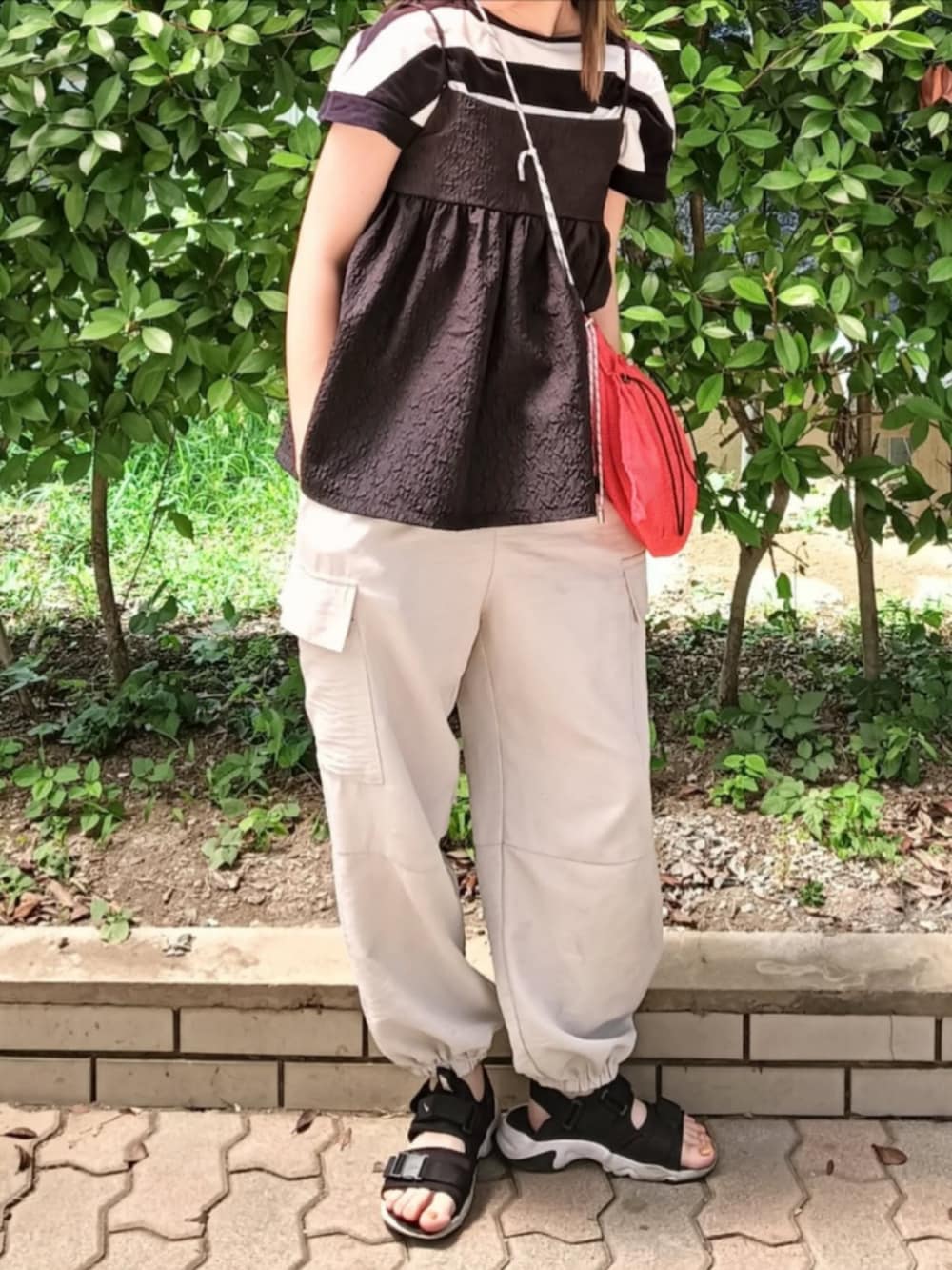 ブラック系のTシャツ/カットソー、ブラック系のTシャツ/カットソー、オレンジ系のショルダーバッグを着用したレディースの夏コーディネートの3枚目の写真