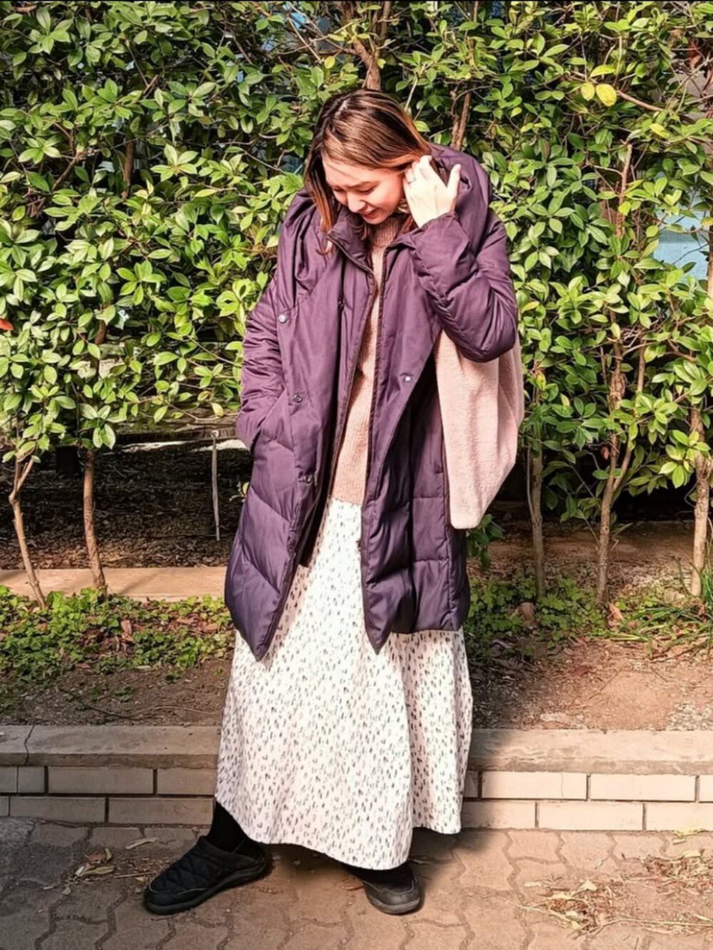 ベージュ系のニット/セーター、ブルー系のダウンジャケット/コート、ベージュ系のショルダーバッグを着用したレディースの冬コーディネートの4枚目の写真