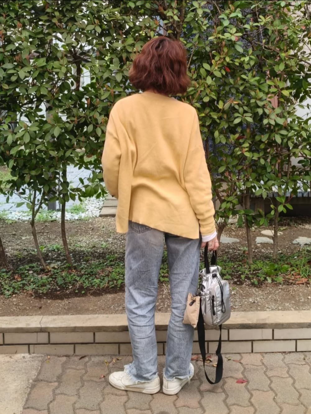 グレー系のTシャツ/カットソー、グリーン系のカーディガン/ボレロ、ブルー系のデニムパンツを着用したレディースの春コーディネートの3枚目の写真