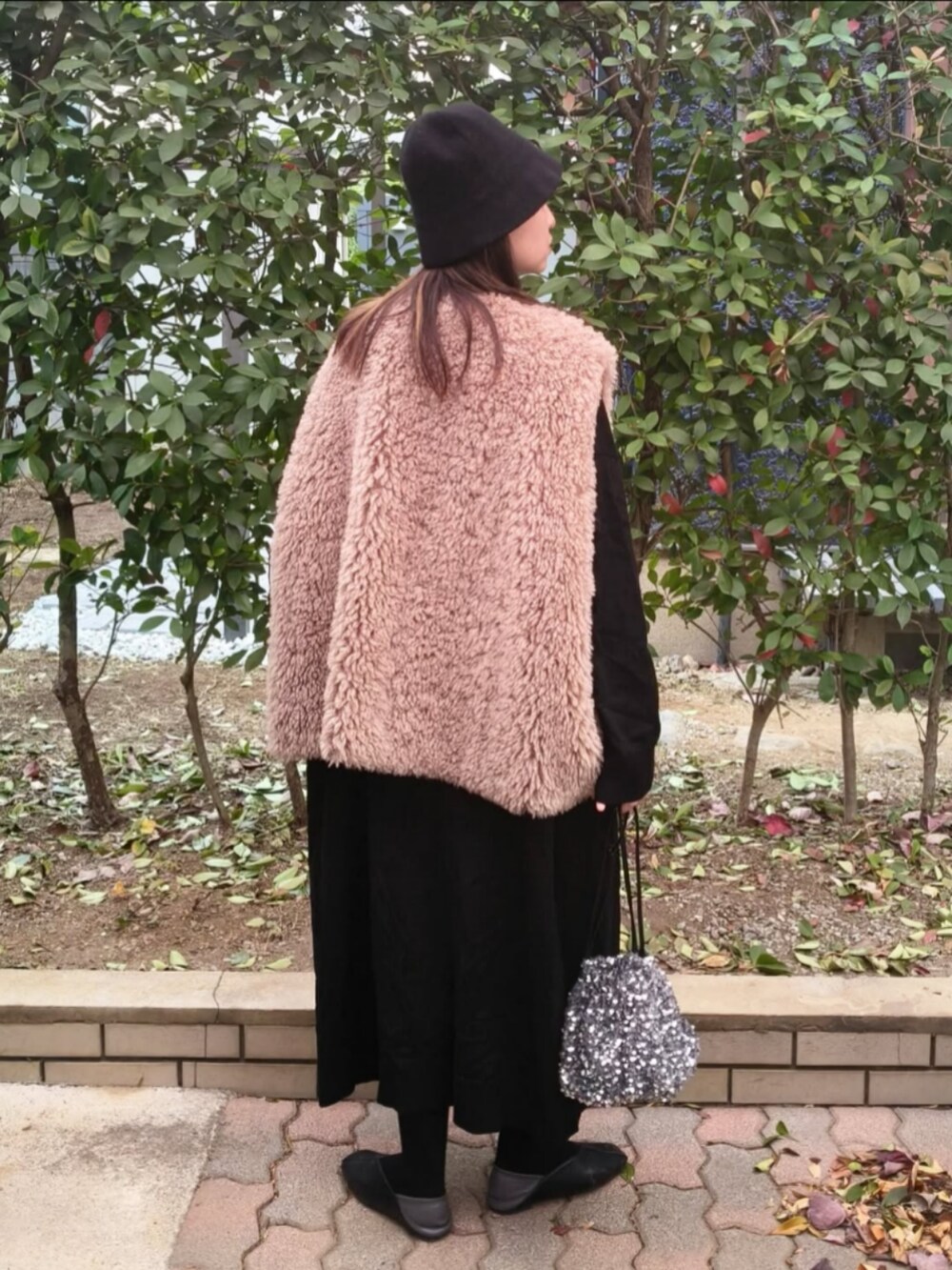 ブラック系のベスト、ブラック系のワンピース、シルバー系のショルダーバッグを着用したレディースの秋コーディネートの2枚目の写真