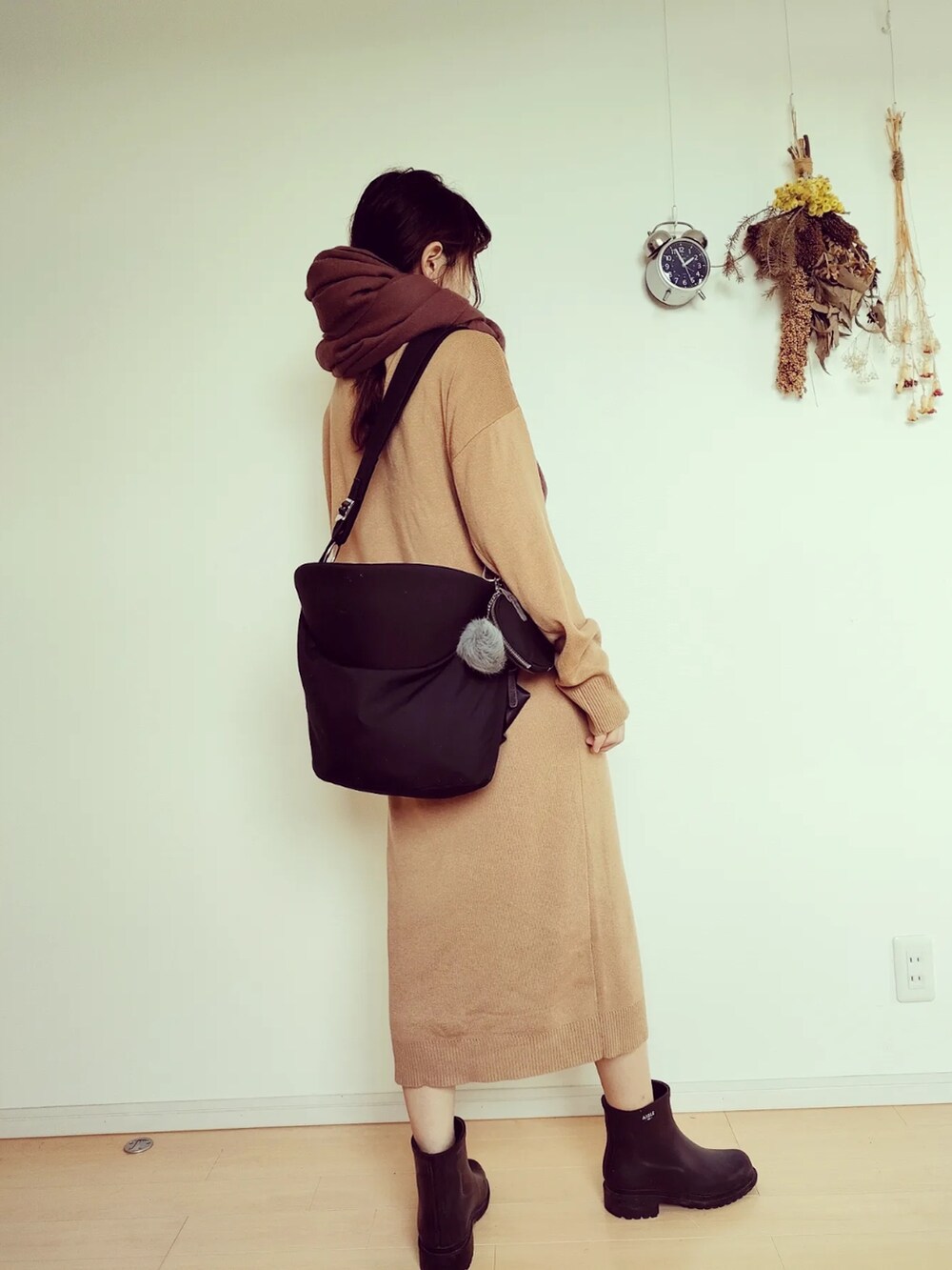 ブラック系のバッグ、ブラック系のレインシューズ、ベージュ系のセットアップを着用したレディースの秋コーディネートの4枚目の写真