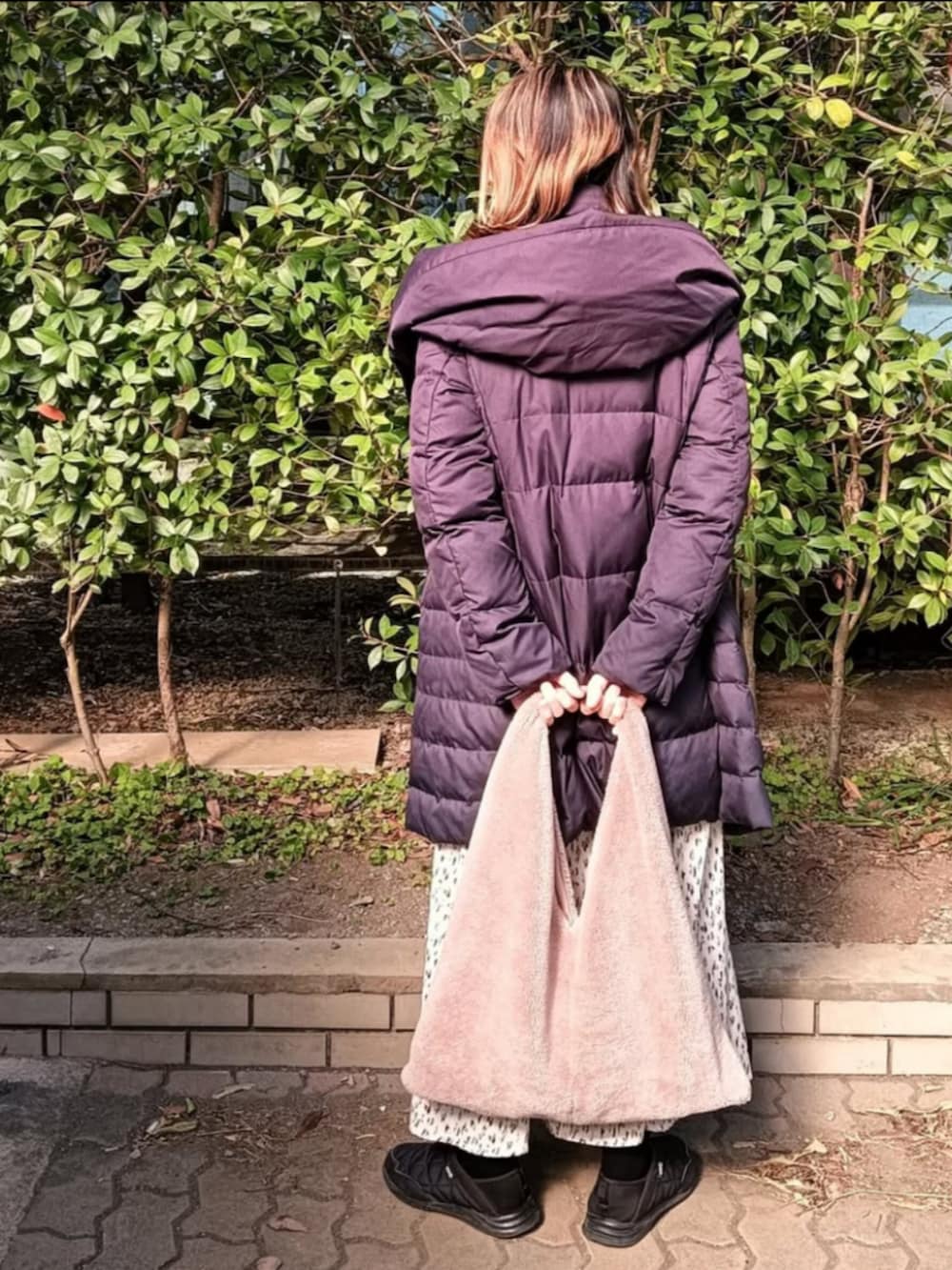 ベージュ系のニット/セーター、ブルー系のダウンジャケット/コート、ベージュ系のショルダーバッグを着用したレディースの冬コーディネートの3枚目の写真