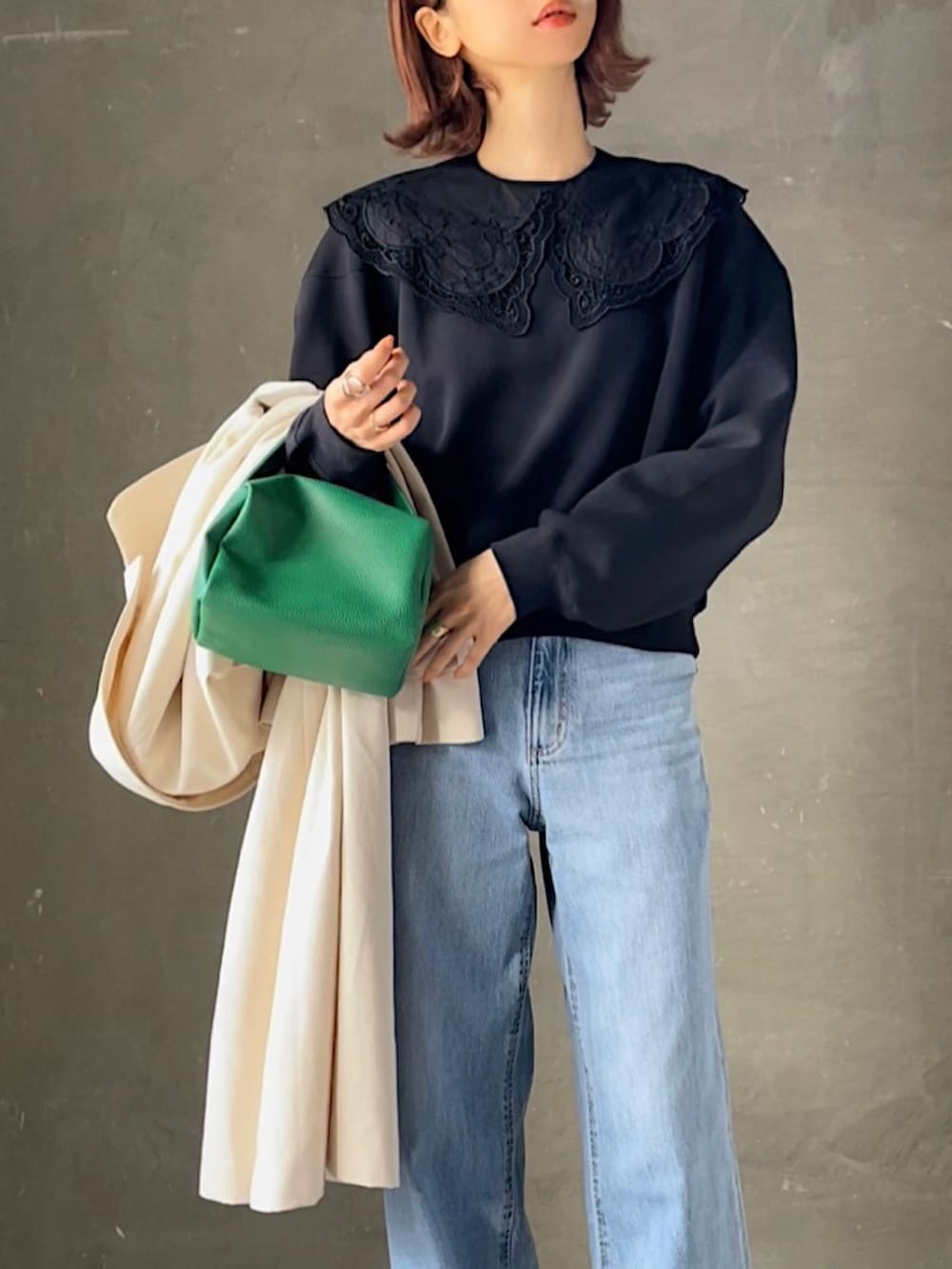 ホワイト系のトレンチコート、ブラック系のスウェット、ブルー系のデニムパンツを着用したレディースの春コーディネートの3枚目の写真