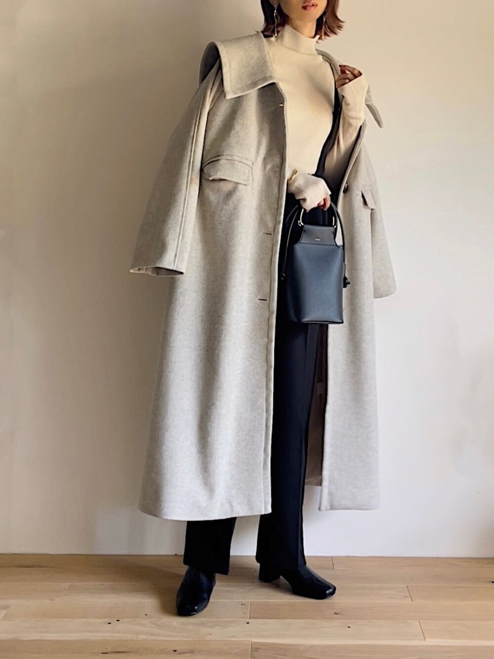 ベージュ系のステンカラーコート、ベージュ系のニット/セーター、ブラック系のその他パンツを着用したレディースの秋コーディネートの3枚目の写真