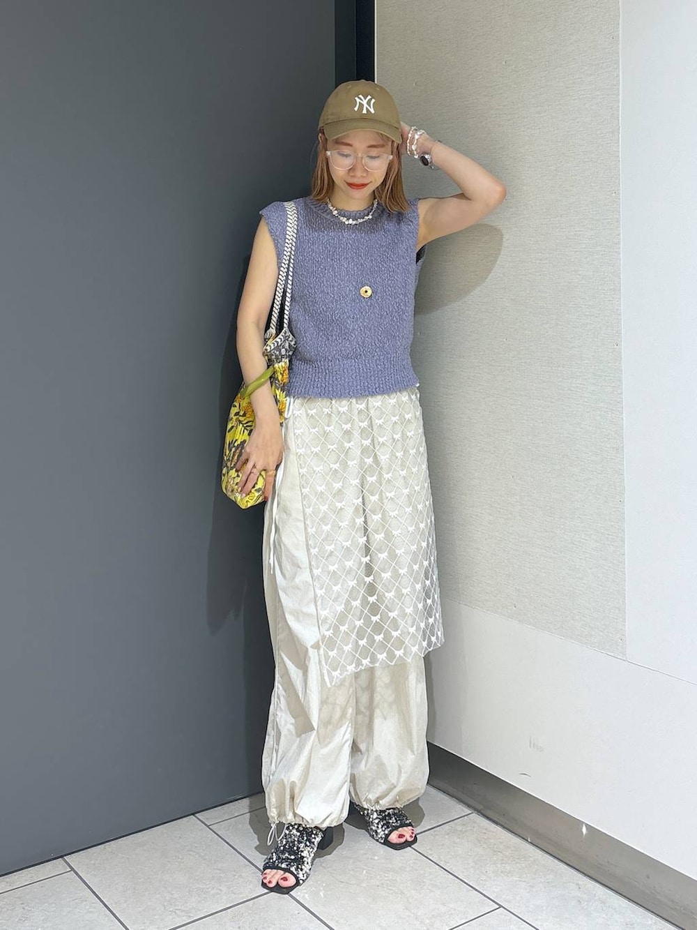 イエロー系のトートバッグ、シルバー系のサンダル、ホワイト系のその他パンツを着用したレディースの夏コーディネートの7枚目の写真