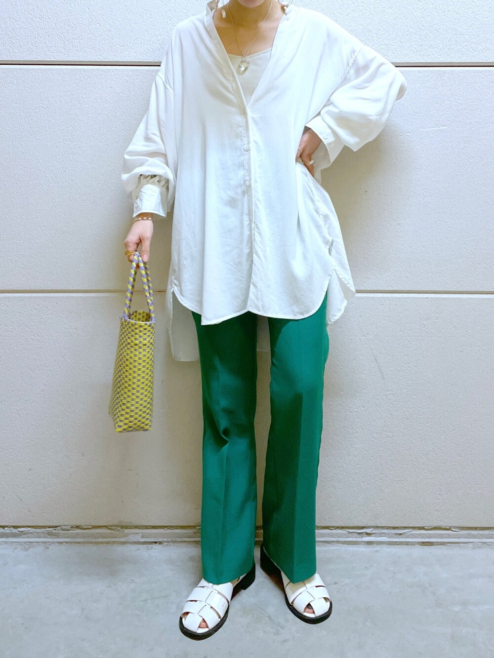 グリーン系のスラックス、パープル系のかごバッグ、ホワイト系のサンダルを着用したレディースの春コーディネートの2枚目の写真