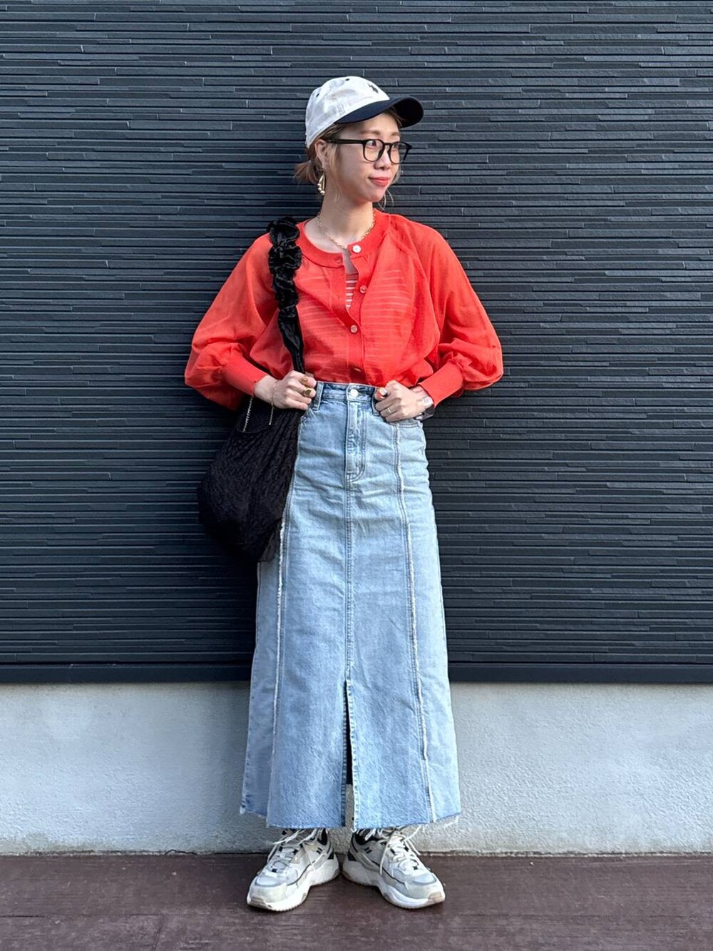 ブラック系のトートバッグ、オレンジ系のカーディガン/ボレロ、ブルー系のスカートを着用したレディースの夏コーディネートの6枚目の写真