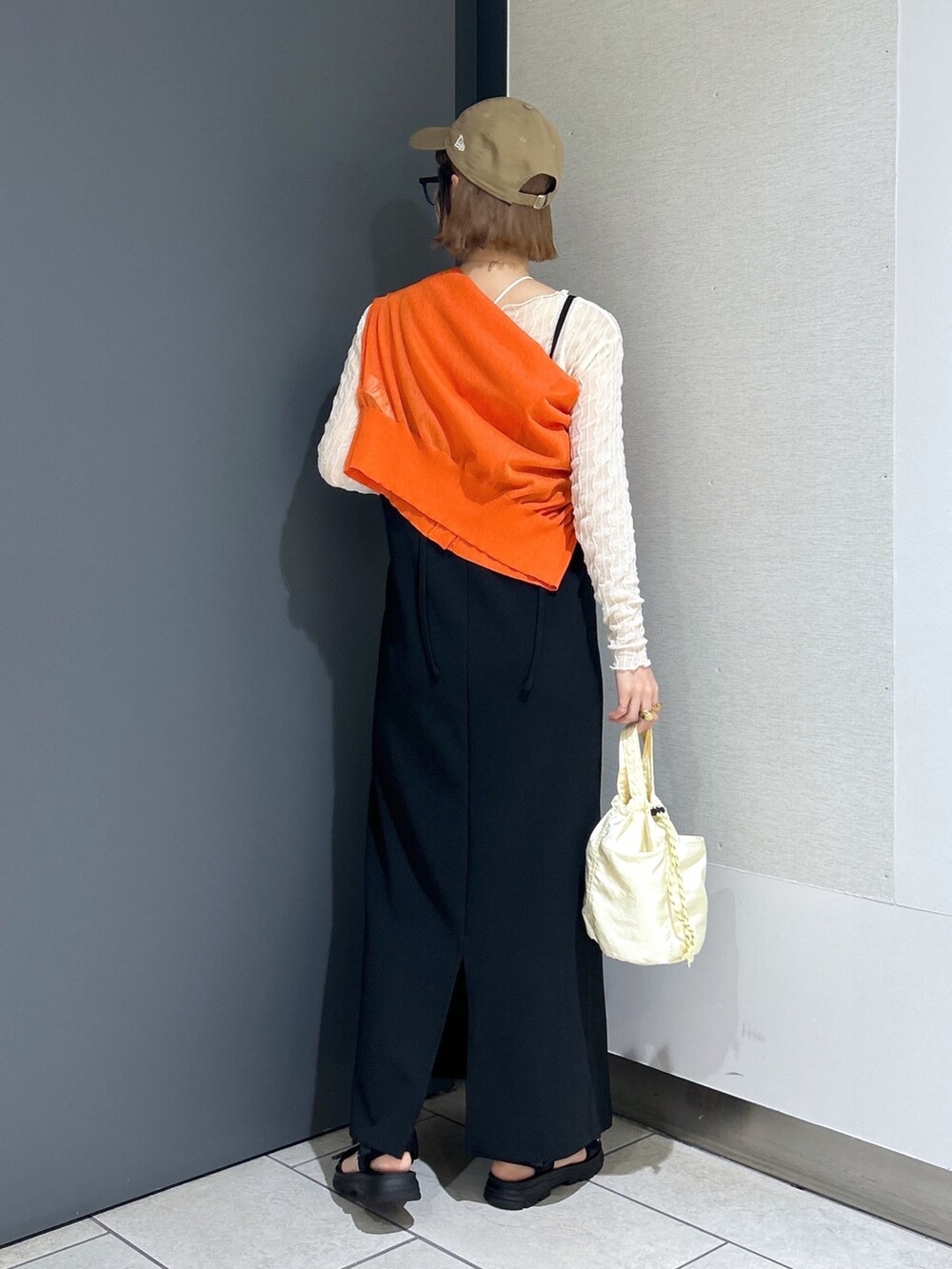 ブラック系のサンダル、オレンジ系のカーディガン/ボレロ、ホワイト系のTシャツ/カットソーを着用したレディースの春コーディネートの4枚目の写真