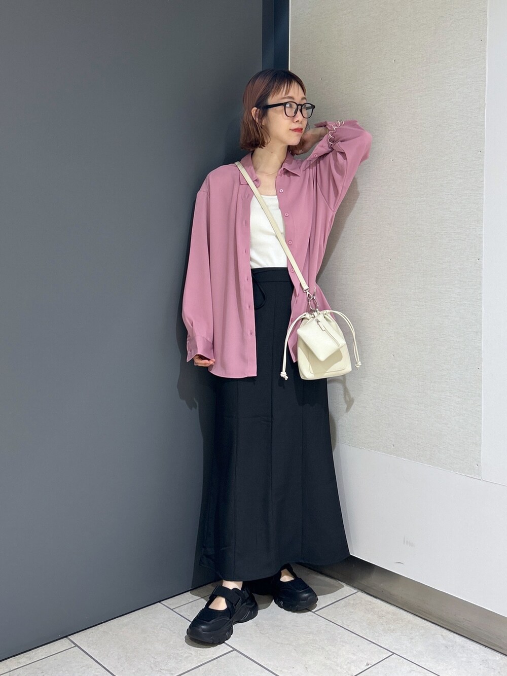 ブラック系のスカート、ピンク系のトップス、ホワイト系のトップスを着用したレディースの春コーディネートの2枚目の写真