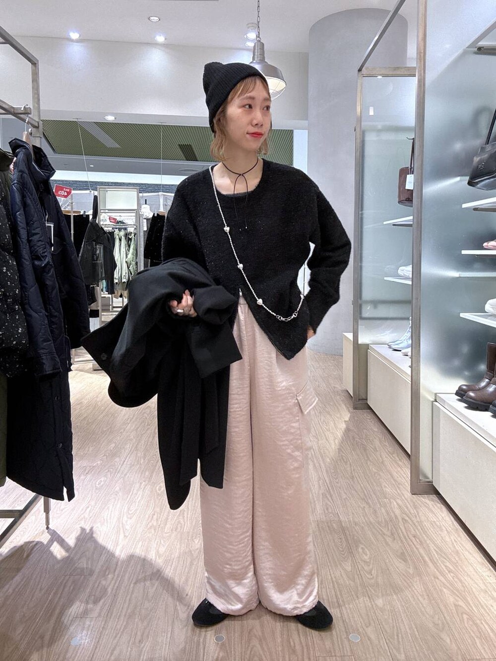 ブラック系のステンカラーコート、ピンク系のカーゴパンツ、ブラック系のニット/セーターを着用したレディースの冬コーディネートの9枚目の写真