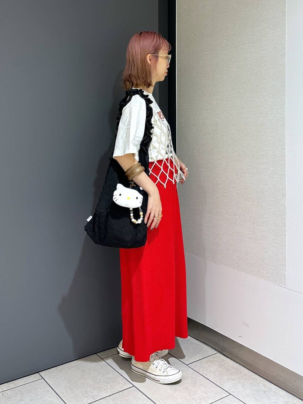 ブラック系のトートバッグ、レッド系のスカート、ホワイト系のベストを着用したレディースの夏コーディネートの5枚目の写真