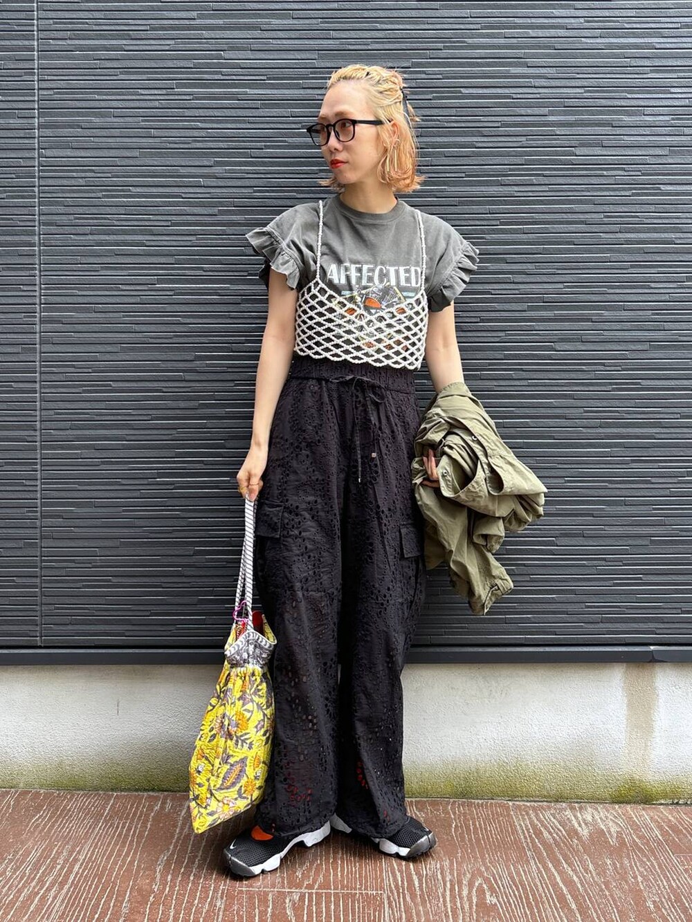 ブラック系のカーゴパンツ、イエロー系のトートバッグ、ホワイト系のベストを着用したレディースの春コーディネートの2枚目の写真