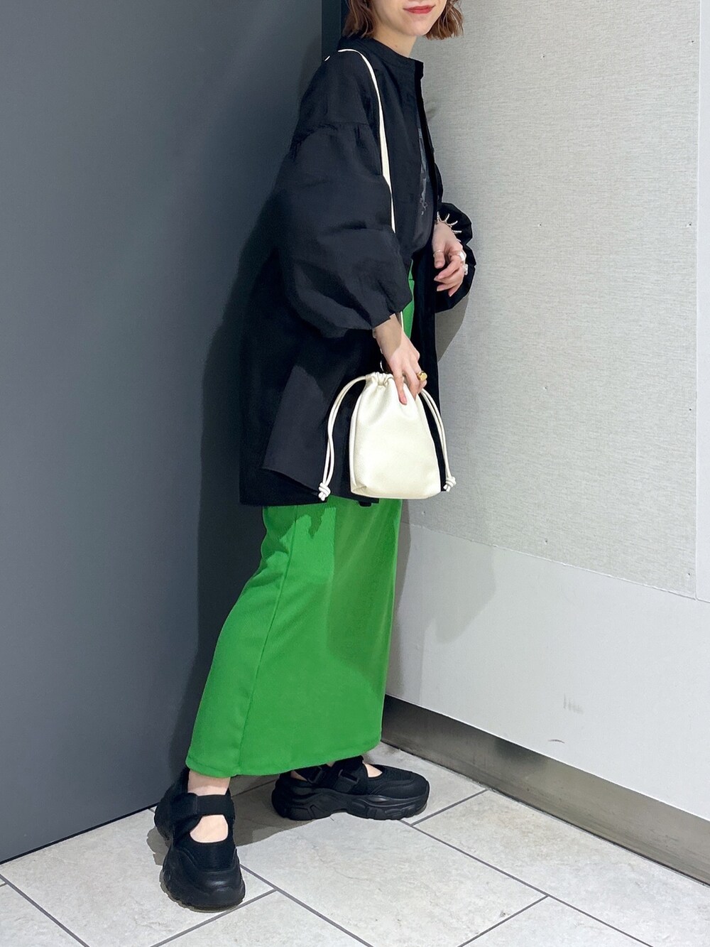 ブラック系のバッグ、グリーン系のスカート、グレー系のTシャツ/カットソーを着用したレディースの春コーディネートの3枚目の写真