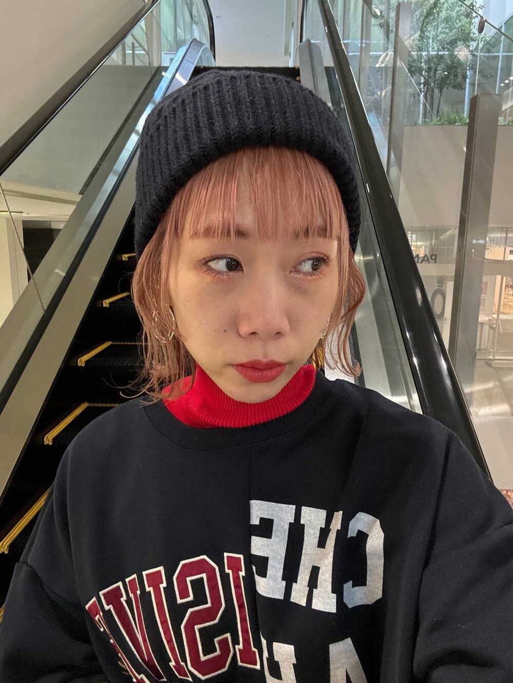 レッド系のニット/セーター、ホワイト系のスニーカー、ピンク系のカーゴパンツを着用したレディースの冬コーディネートの6枚目の写真