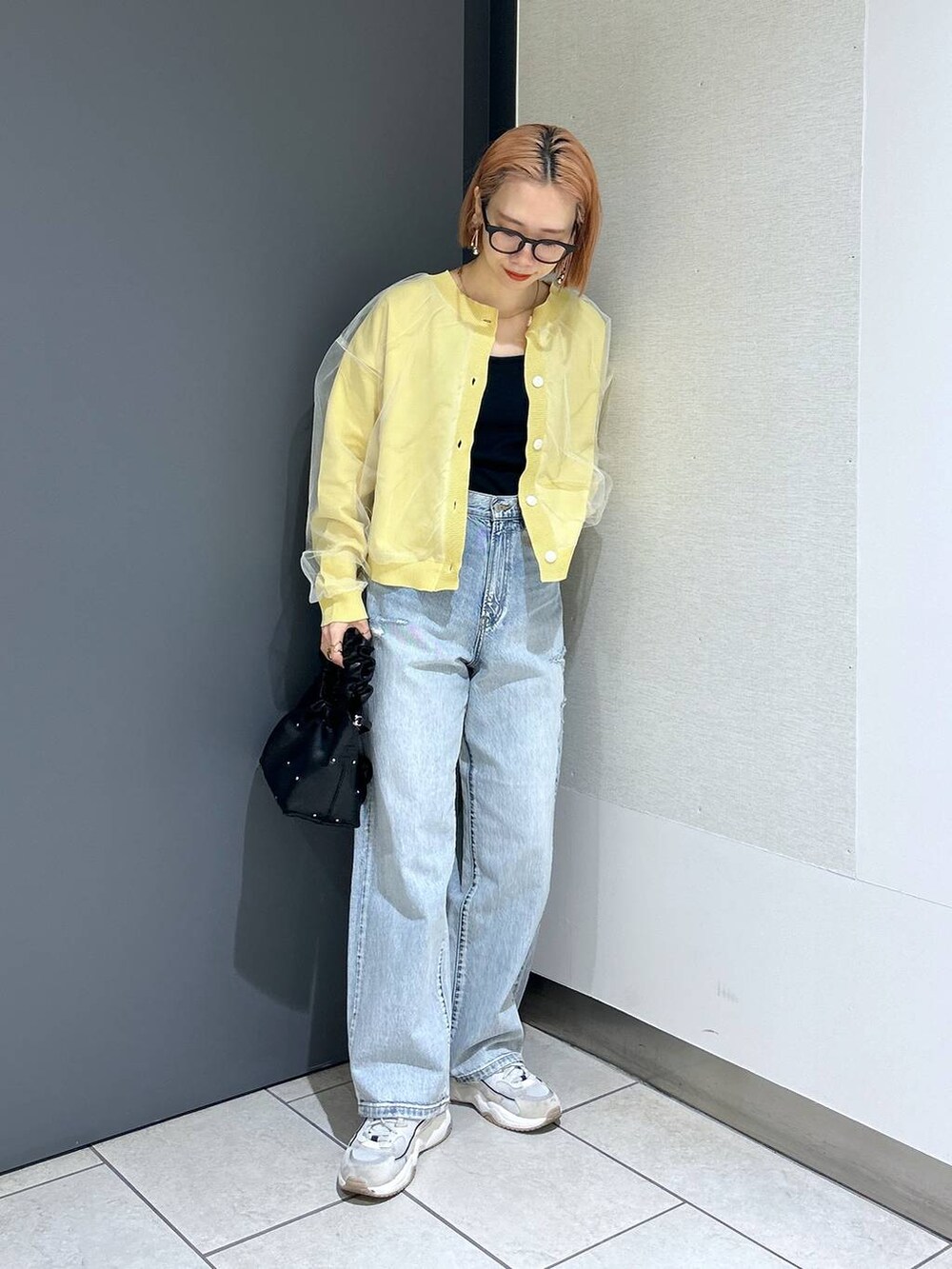 ブラック系のハンドバッグ、イエロー系のニット/セーター、ブラック系のTシャツ/カットソーを着用したレディースの春コーディネートの3枚目の写真