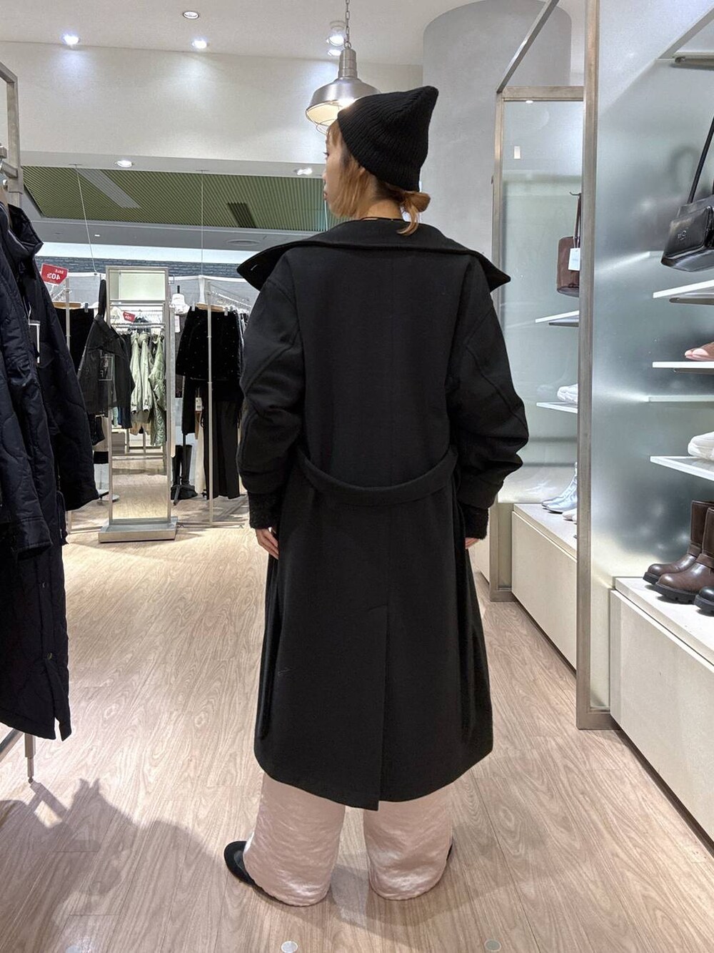 ブラック系のステンカラーコート、ピンク系のカーゴパンツ、ブラック系のニット/セーターを着用したレディースの冬コーディネートの5枚目の写真