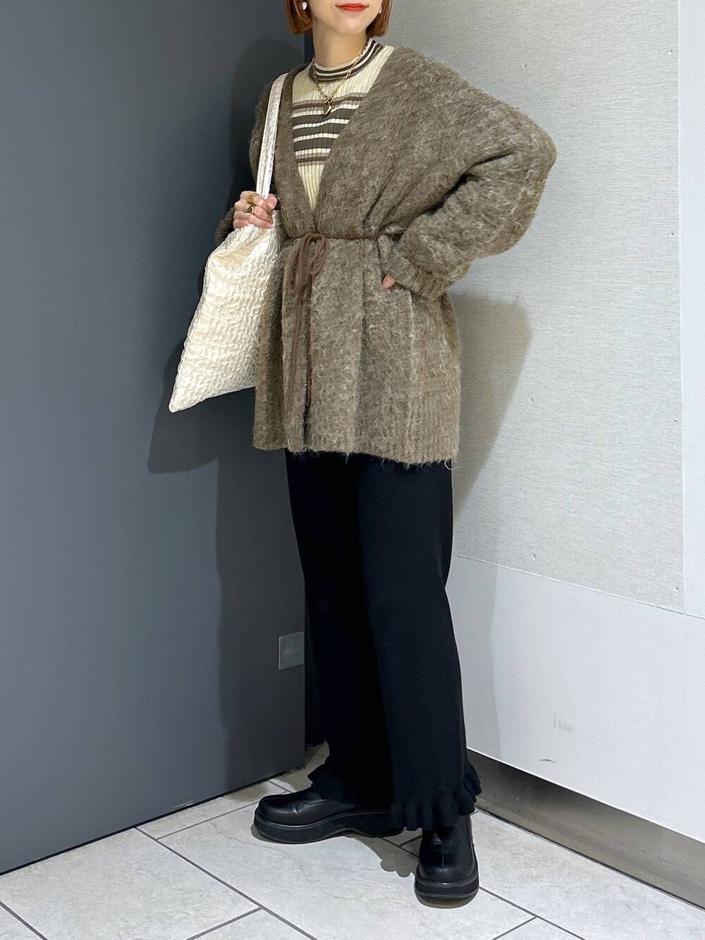 ホワイト系のトートバッグ、ブラック系のその他パンツ、ブラック系のブーツを着用したレディースの秋コーディネートの3枚目の写真