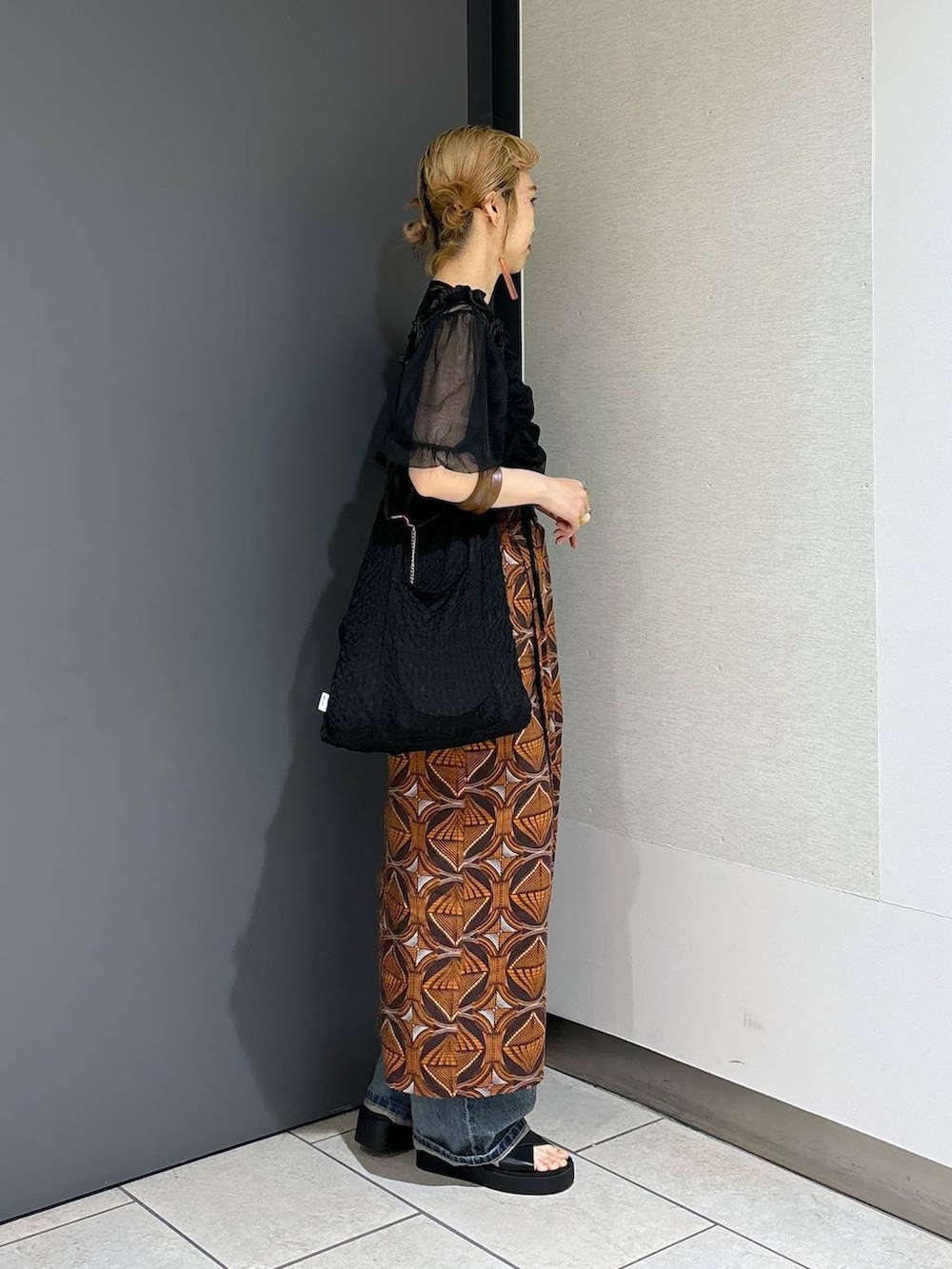 ブラック系のトートバッグ、ブラウン系のスカート、ブラック系のサンダルを着用したレディースの春コーディネートの3枚目の写真