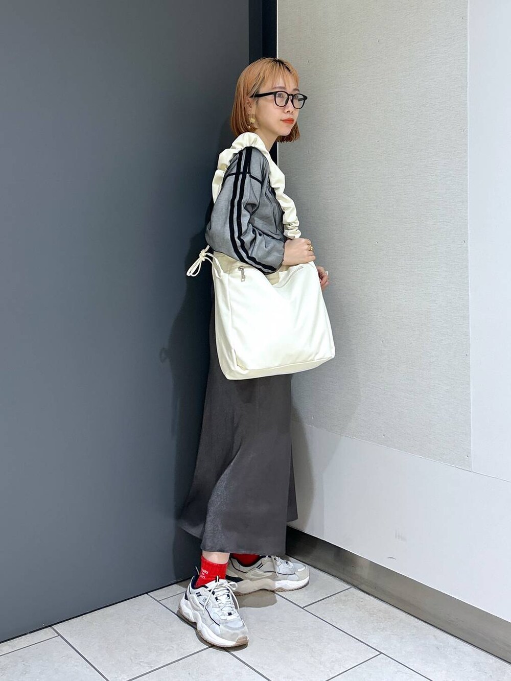 ベージュ系のトートバッグ、ブラック系のTシャツ/カットソー、グレー系のスカートを着用したレディースの春コーディネートの6枚目の写真
