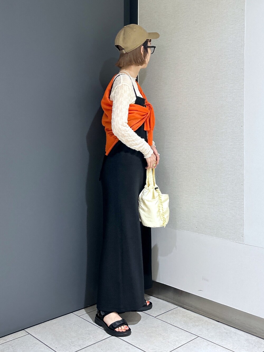 ブラック系のサンダル、オレンジ系のカーディガン/ボレロ、ホワイト系のTシャツ/カットソーを着用したレディースの春コーディネートの3枚目の写真