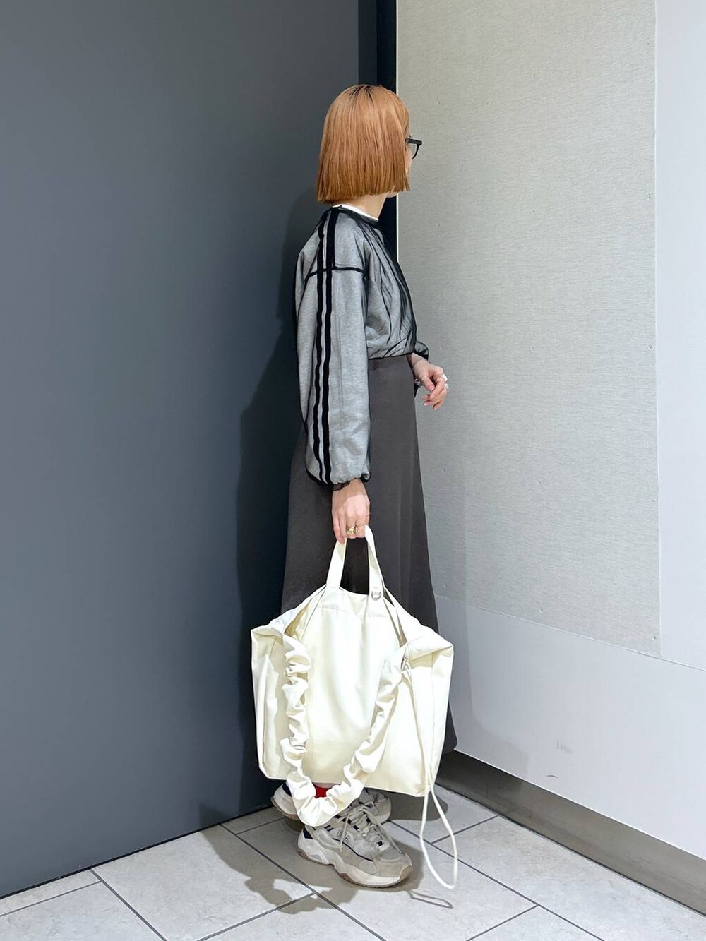 ベージュ系のトートバッグ、ブラック系のTシャツ/カットソー、グレー系のスカートを着用したレディースの春コーディネートの5枚目の写真