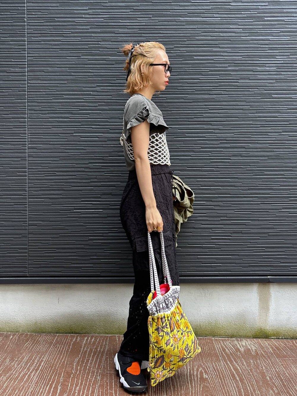 ブラック系のカーゴパンツ、イエロー系のトートバッグ、ホワイト系のベストを着用したレディースの春コーディネートの4枚目の写真
