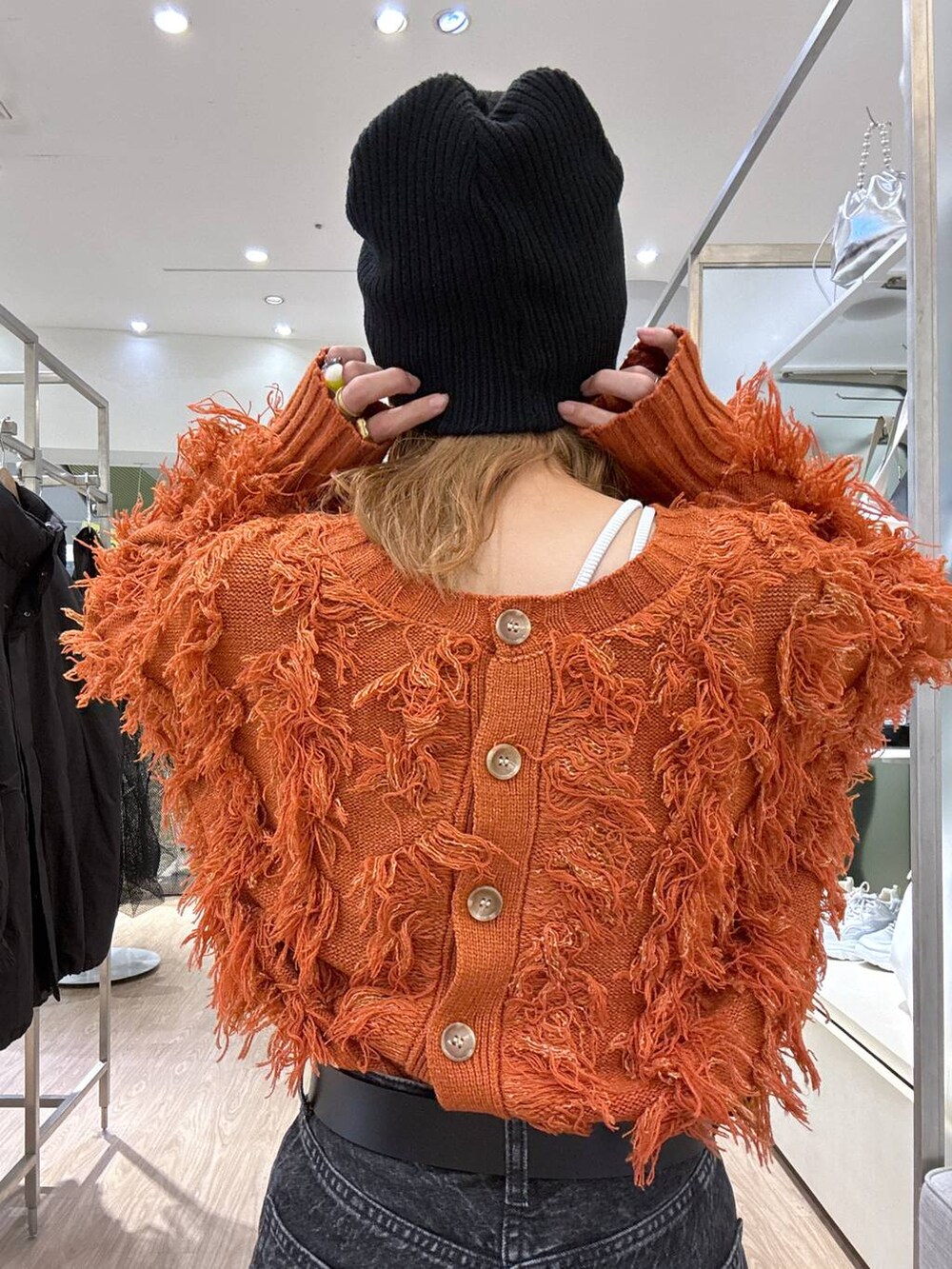 オレンジ系のカーディガン/ボレロ、ブラック系のスニーカー、ブラック系のベルトを着用したレディースの冬コーディネートの6枚目の写真