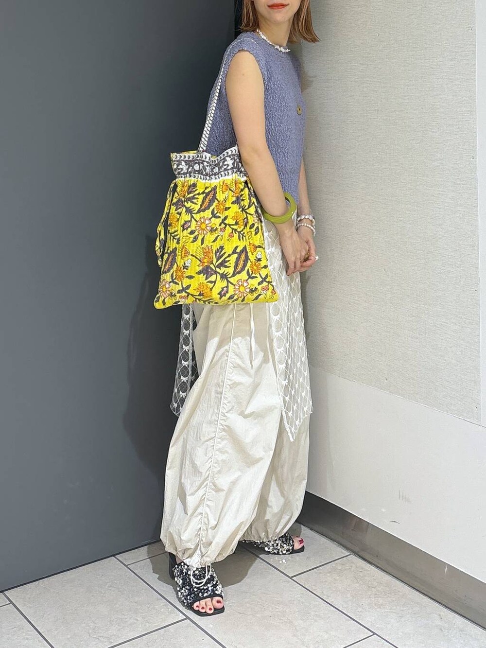 イエロー系のトートバッグ、シルバー系のサンダル、ホワイト系のその他パンツを着用したレディースの夏コーディネートの6枚目の写真