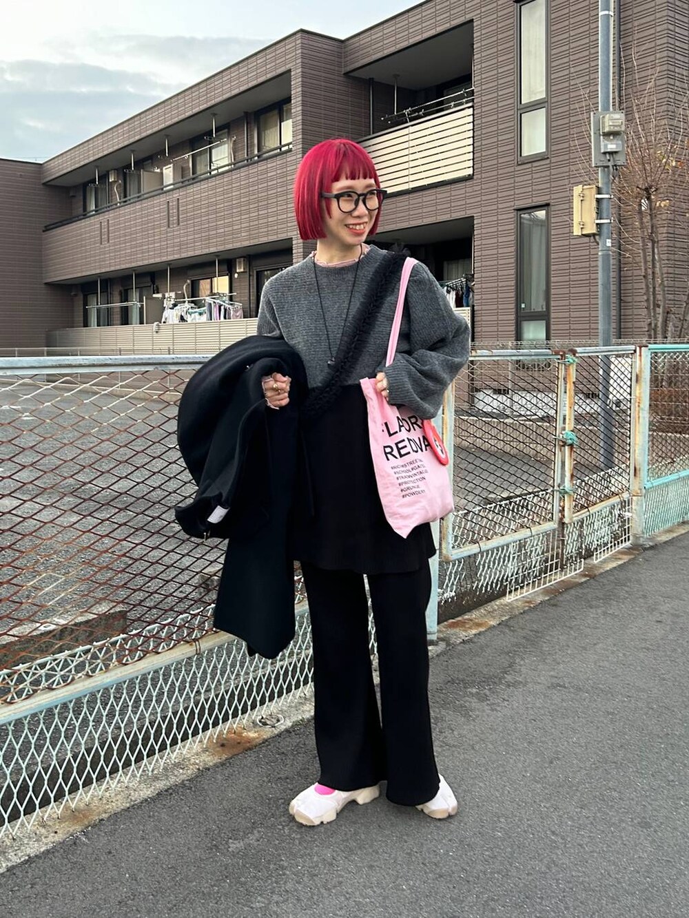 ピンク系のTシャツ/カットソー、グレー系のニット/セーター、ブラック系のスカートを着用したレディースの冬コーディネートの4枚目の写真