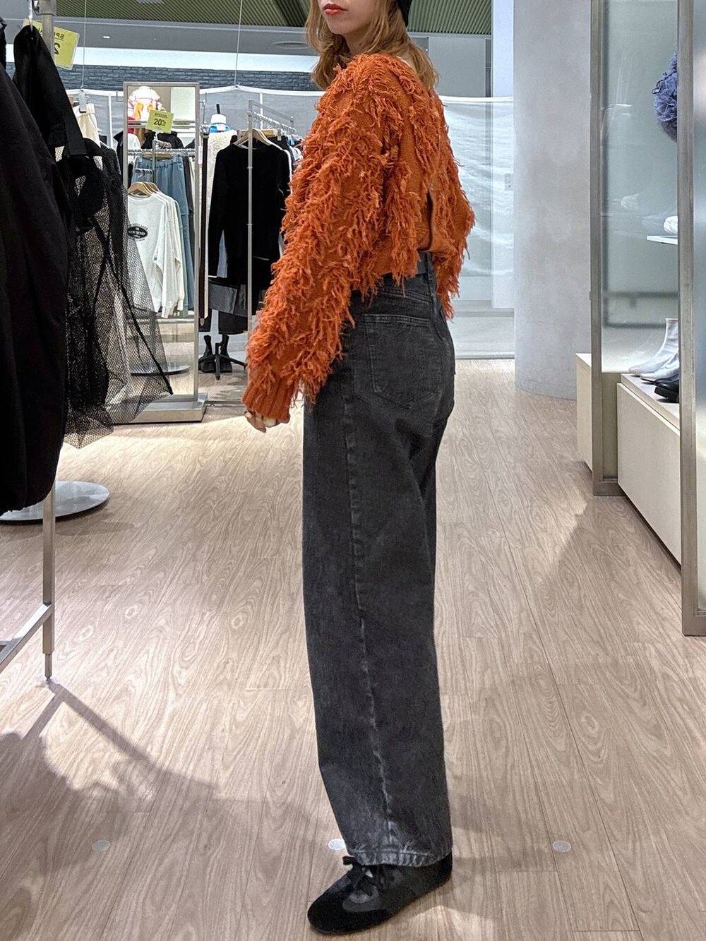 オレンジ系のカーディガン/ボレロ、ブラック系のスニーカー、ブラック系のベルトを着用したレディースの冬コーディネートの3枚目の写真