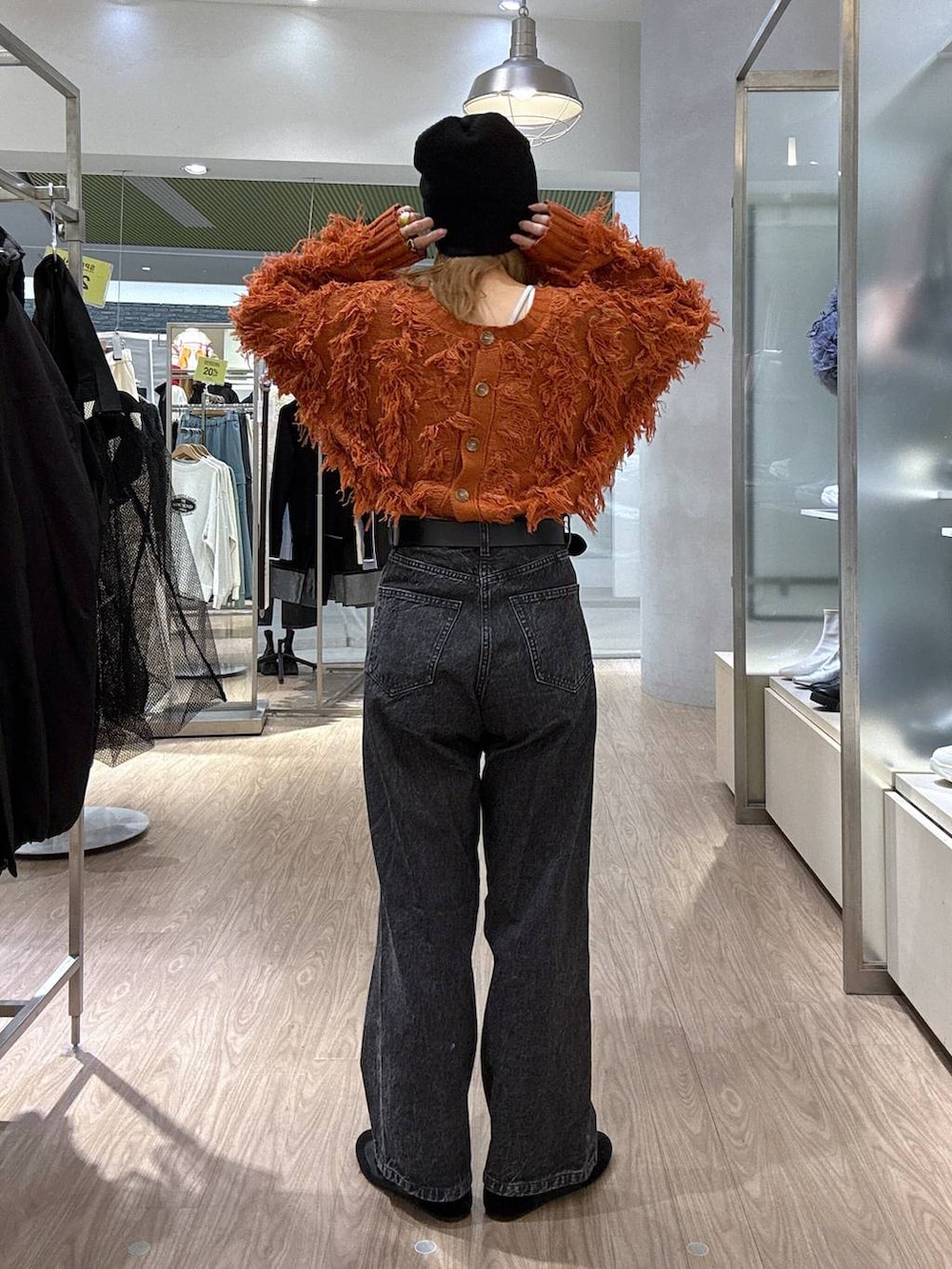 オレンジ系のカーディガン/ボレロ、ブラック系のスニーカー、ブラック系のベルトを着用したレディースの冬コーディネートの4枚目の写真