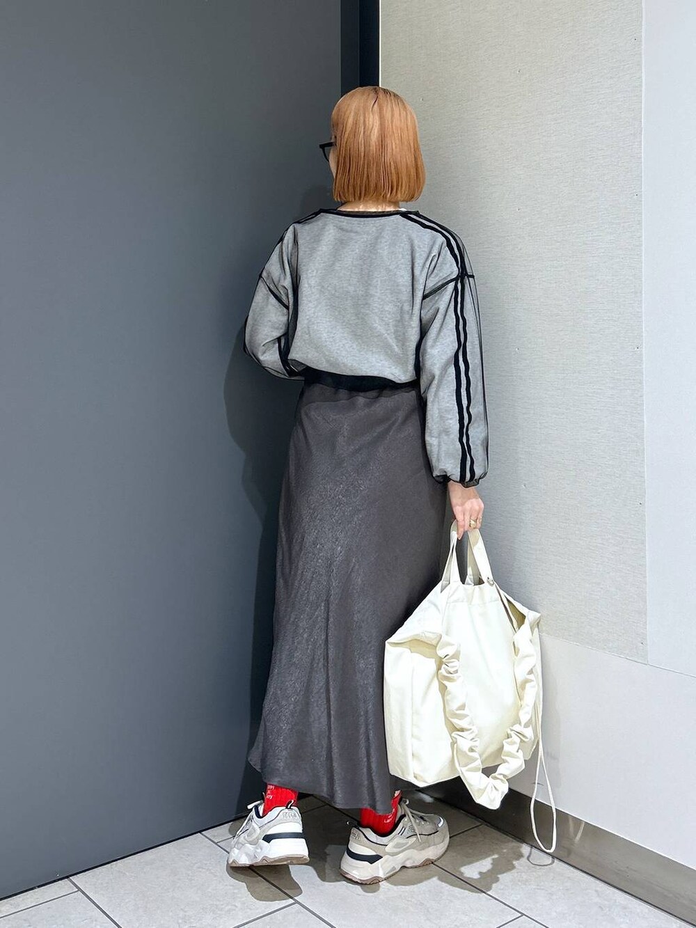 ベージュ系のトートバッグ、ブラック系のTシャツ/カットソー、グレー系のスカートを着用したレディースの春コーディネートの4枚目の写真