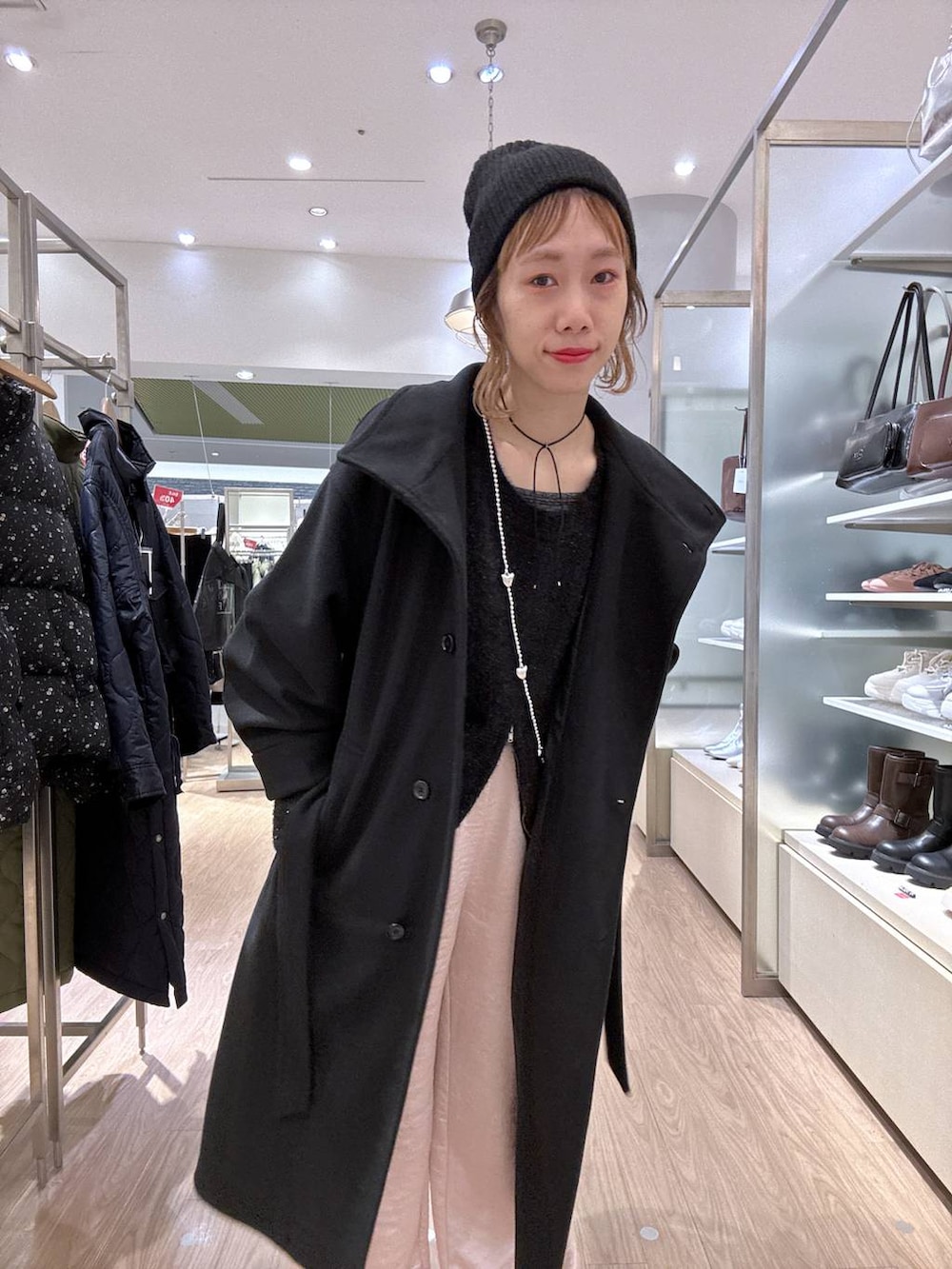 ブラック系のステンカラーコート、ピンク系のカーゴパンツ、ブラック系のニット/セーターを着用したレディースの冬コーディネートの3枚目の写真