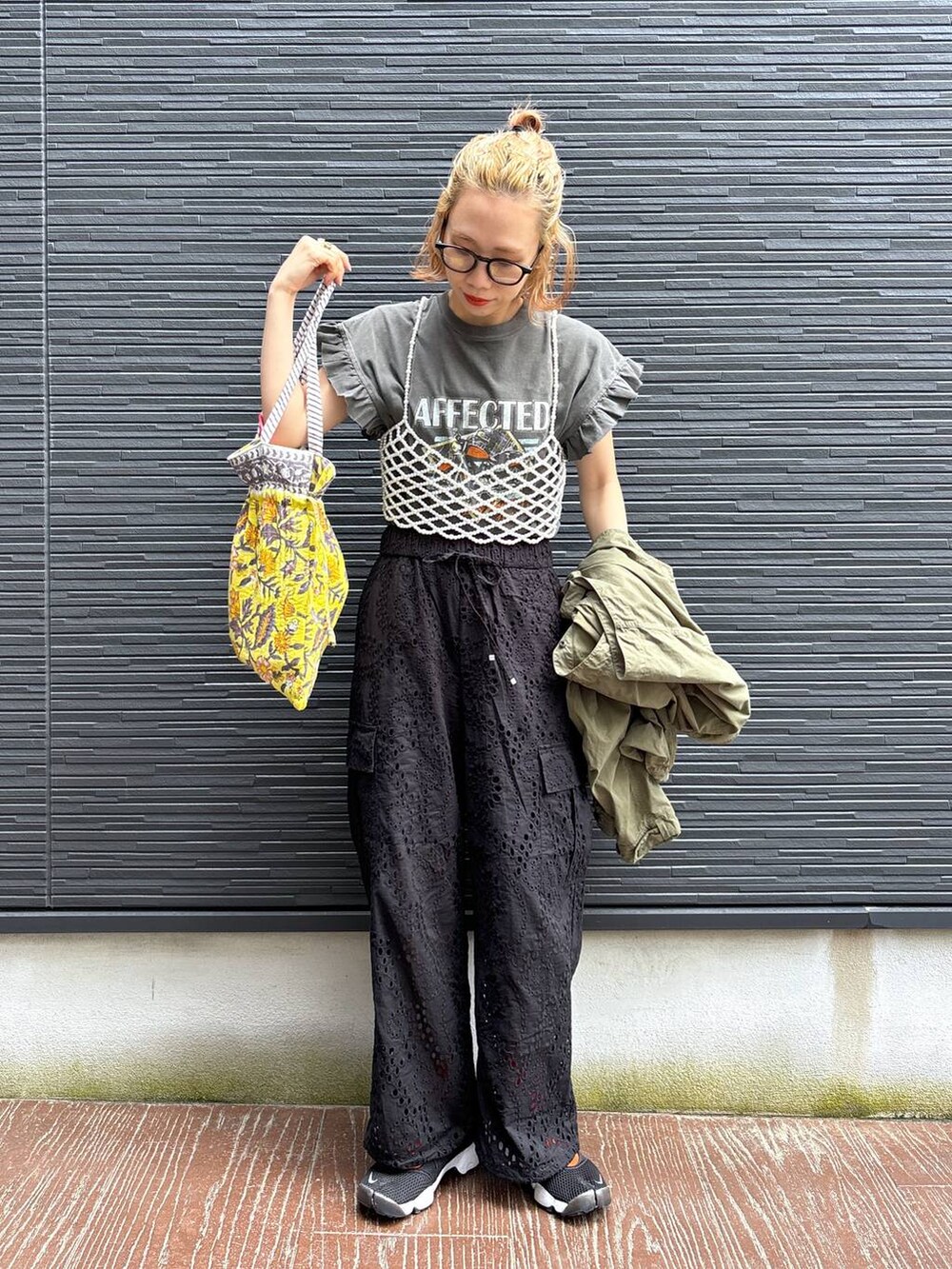 ブラック系のカーゴパンツ、イエロー系のトートバッグ、ホワイト系のベストを着用したレディースの春コーディネートの5枚目の写真