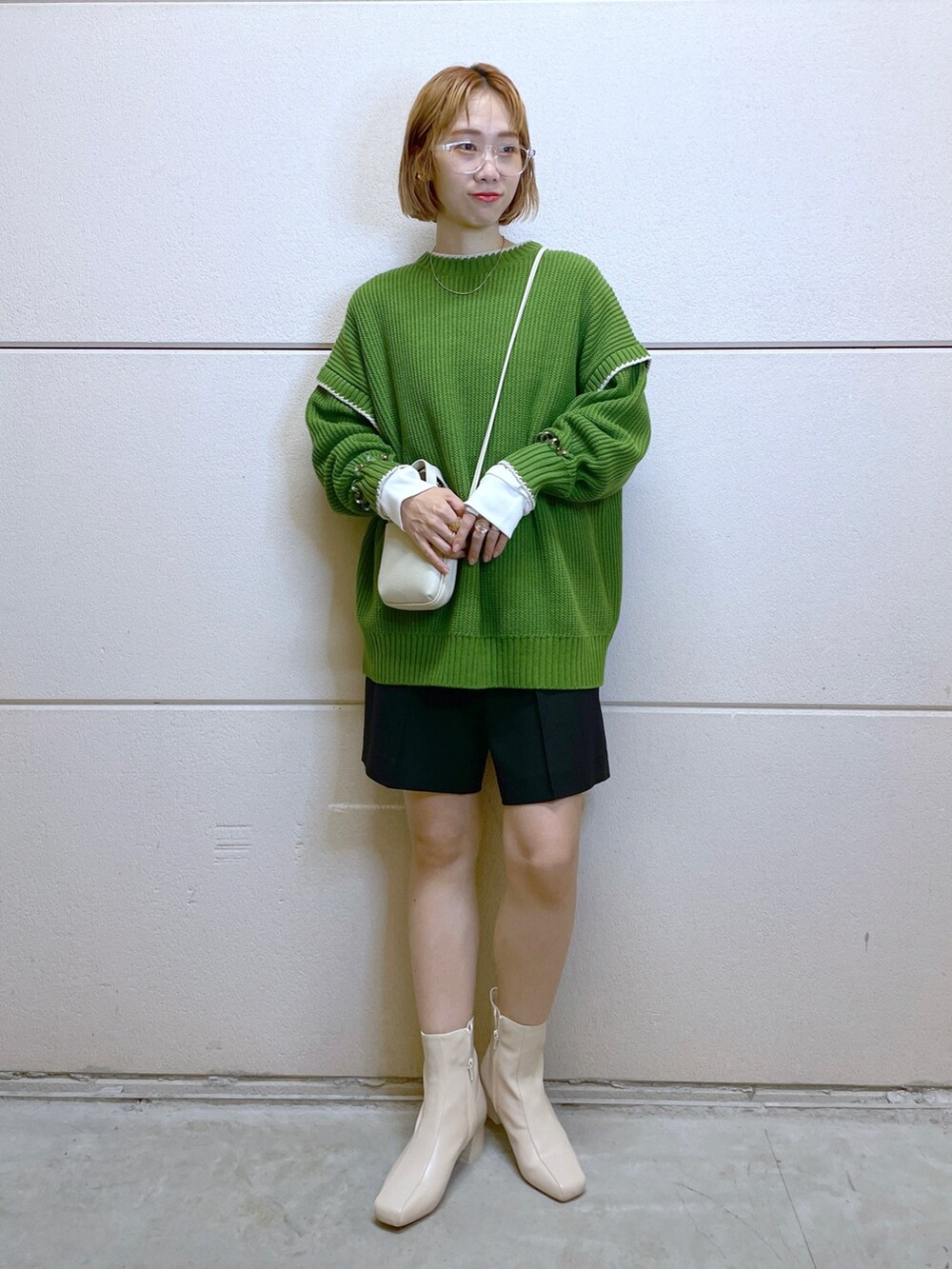 グリーン系のニット/セーター、ブラック系のパンツ、ホワイト系のTシャツ/カットソーを着用したレディースの秋コーディネートの4枚目の写真