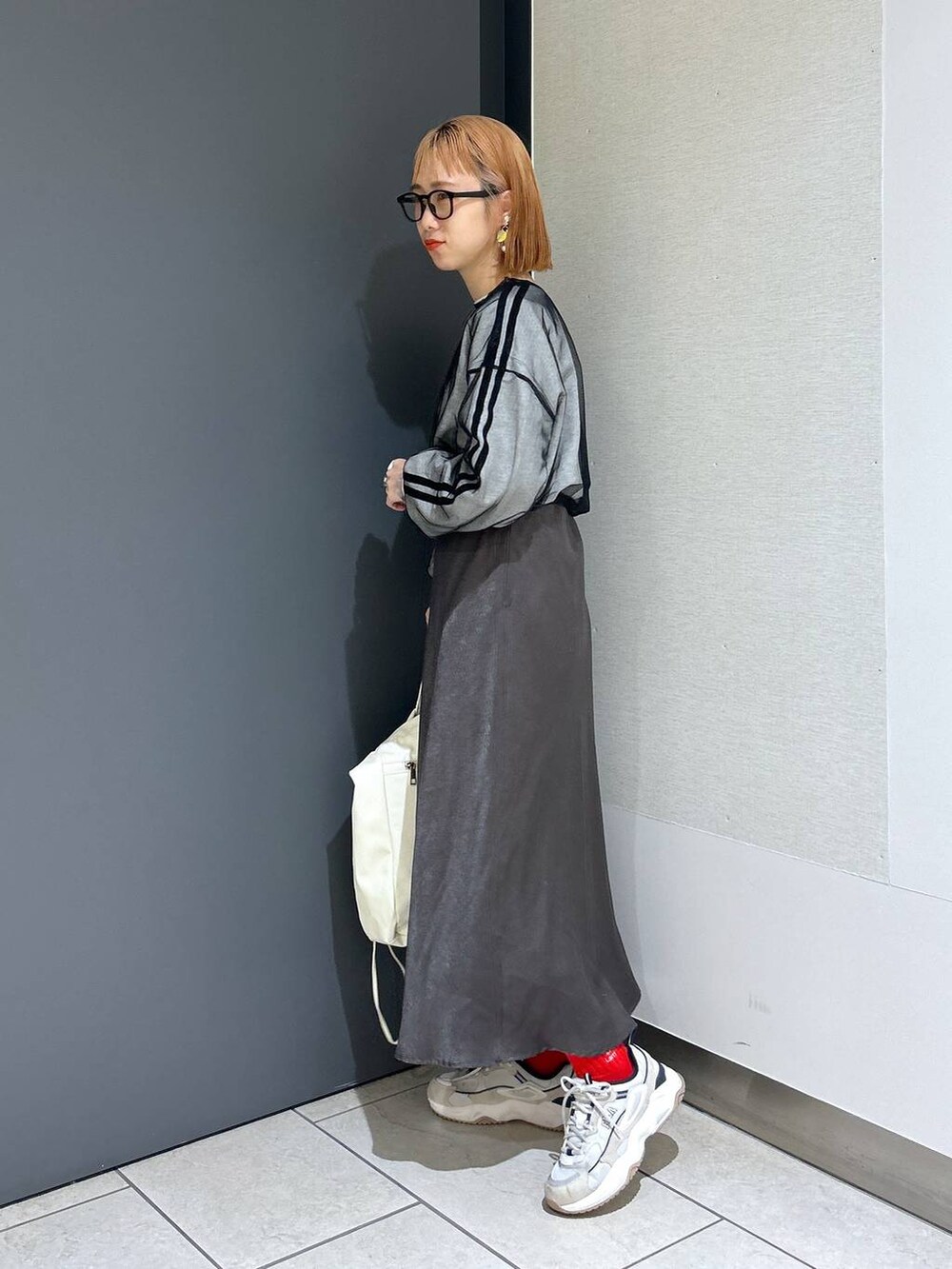 ベージュ系のトートバッグ、ブラック系のTシャツ/カットソー、グレー系のスカートを着用したレディースの春コーディネートの3枚目の写真