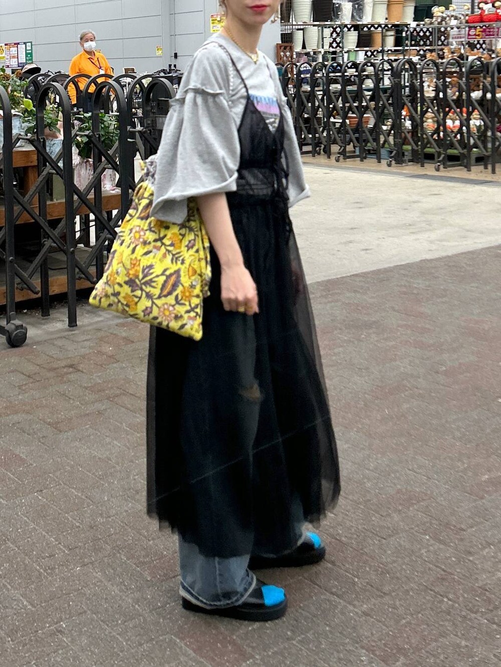 ブラック系のサンダル、ブルー系のデニムパンツ、イエロー系のトートバッグを着用したレディースの春コーディネートの4枚目の写真