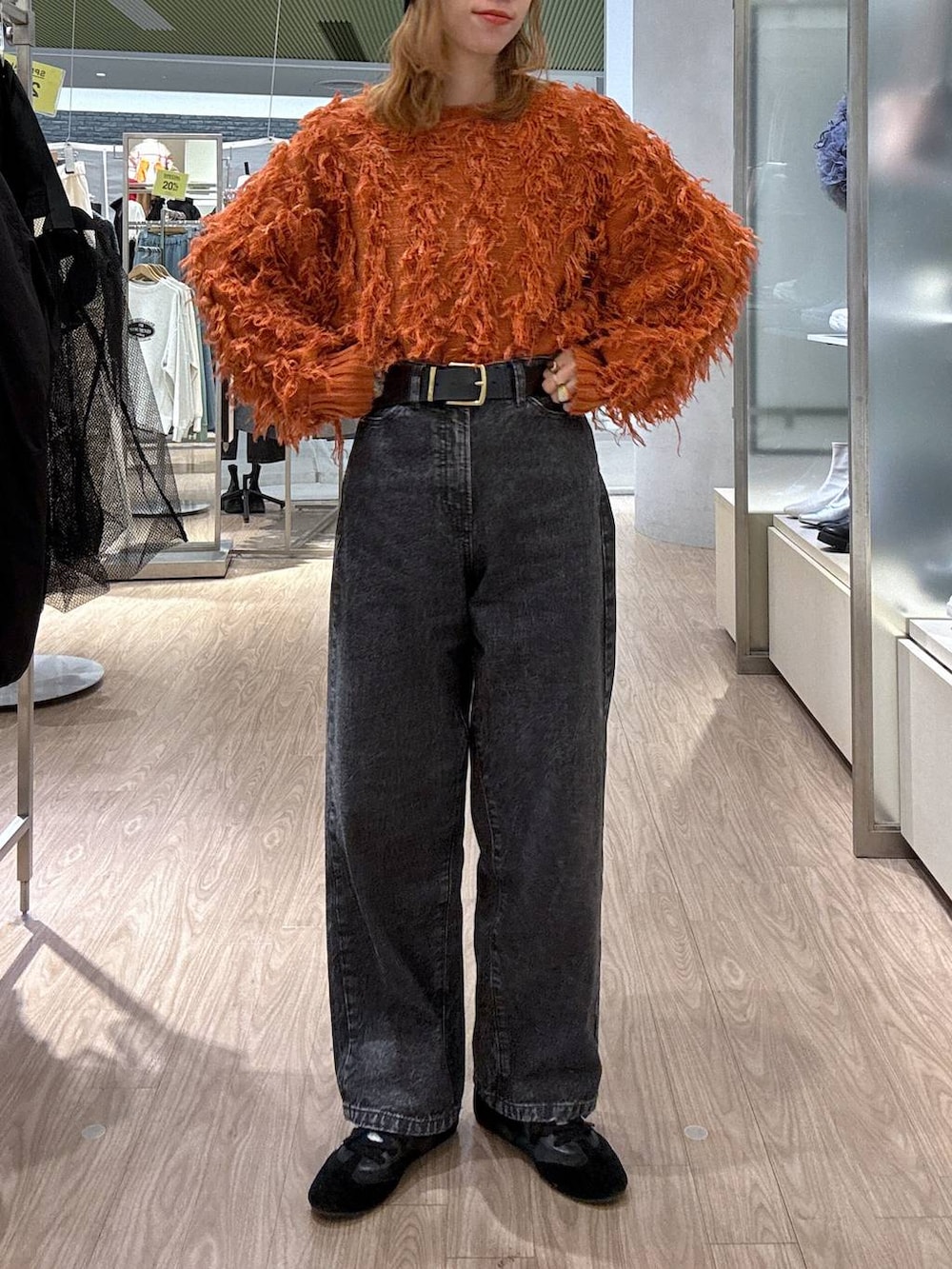 オレンジ系のカーディガン/ボレロ、ブラック系のスニーカー、ブラック系のベルトを着用したレディースの冬コーディネートの2枚目の写真