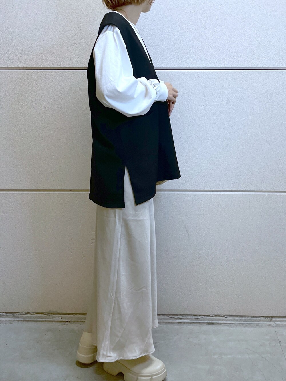 ホワイト系のブーツ、ホワイト系のTシャツ/カットソー、ブラック系のベストを着用したレディースの秋コーディネートの4枚目の写真