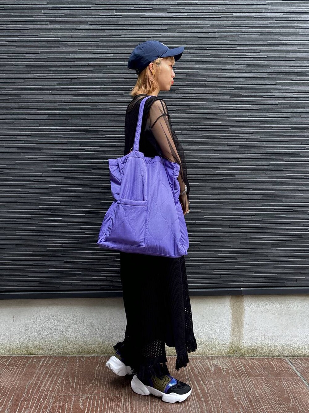 ブラック系のワンピース、パープル系のショルダーバッグ、ブラック系のスカートを着用したレディースの春コーディネートの5枚目の写真