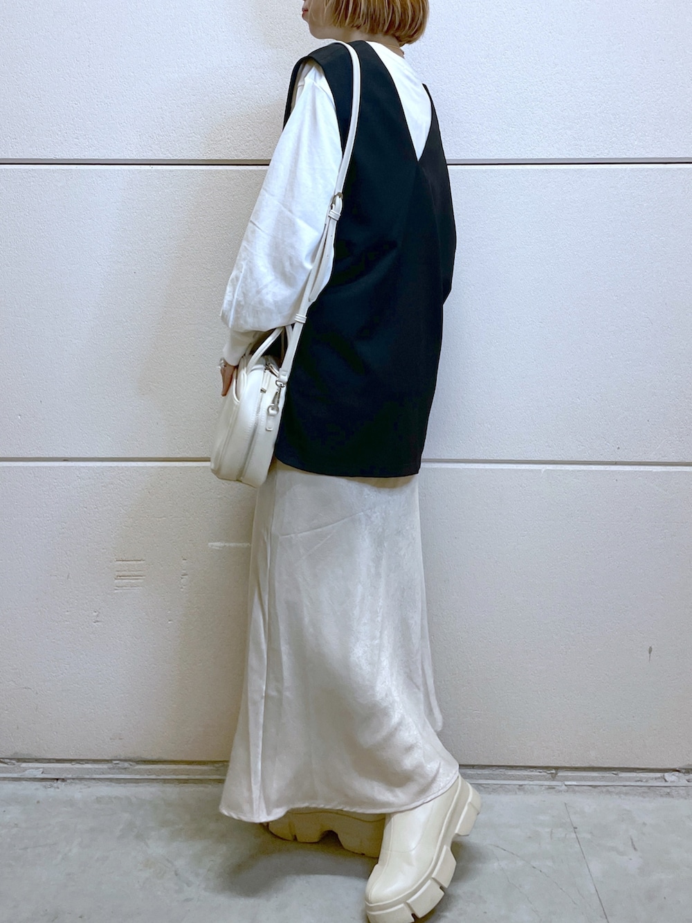 ホワイト系のブーツ、ホワイト系のTシャツ/カットソー、ブラック系のベストを着用したレディースの秋コーディネートの2枚目の写真