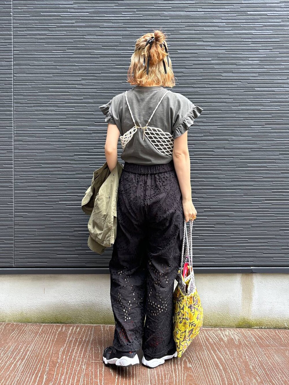 ブラック系のカーゴパンツ、イエロー系のトートバッグ、ホワイト系のベストを着用したレディースの春コーディネートの3枚目の写真