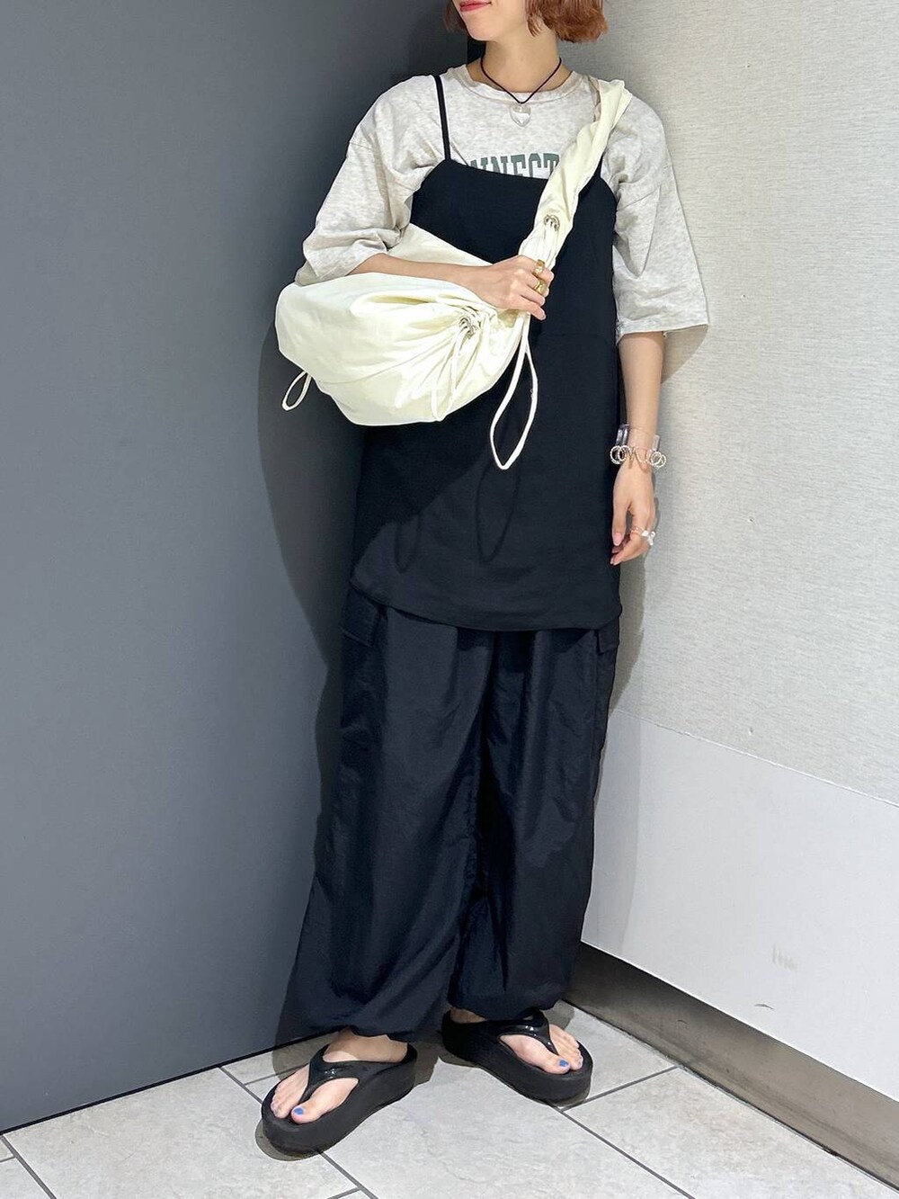 グレー系のTシャツ/カットソー、ブラック系のその他パンツ、ホワイト系のショルダーバッグを着用したレディースの夏コーディネートの3枚目の写真