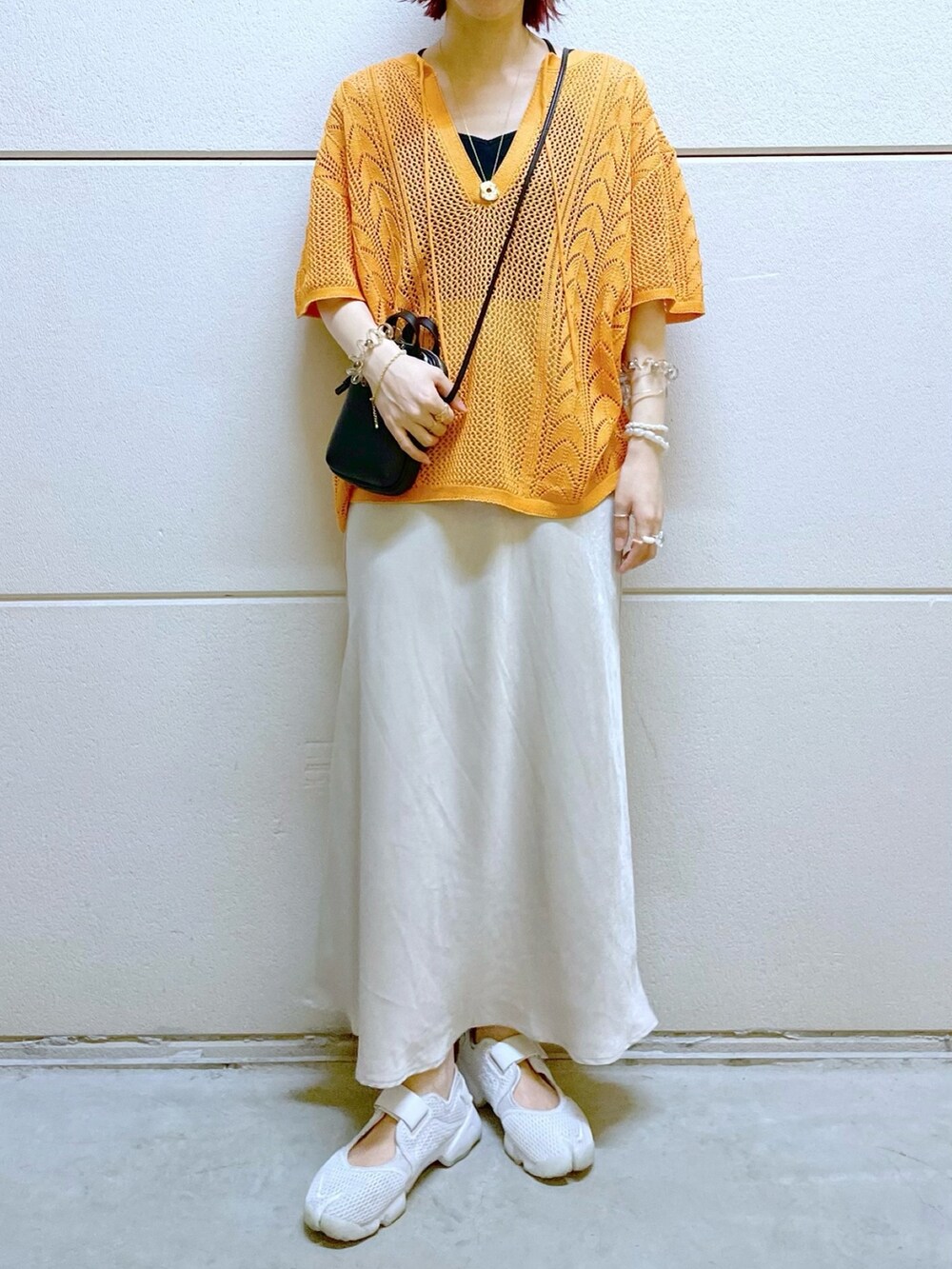 ブラック系のTシャツ/カットソー、オレンジ系のニット/セーター、ブラック系のスカートを着用したレディースの春コーディネートの2枚目の写真