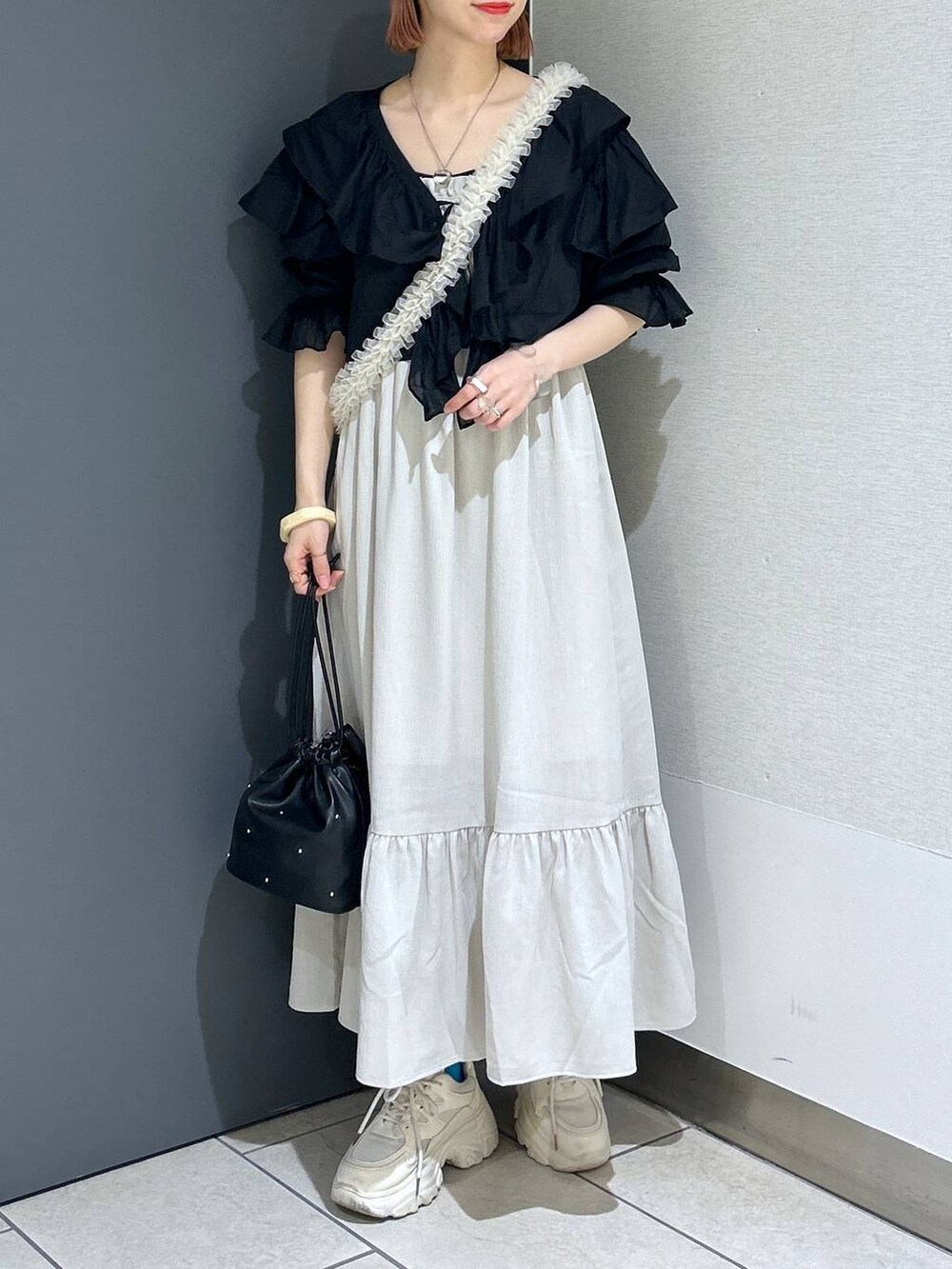 ホワイト系のワンピース、ホワイト系のスニーカー、ブラック系のショルダーバッグを着用したレディースの春コーディネートの7枚目の写真