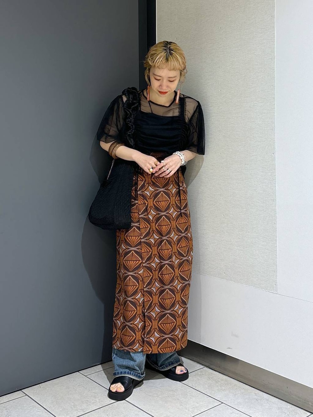 ブラック系のトートバッグ、ブラウン系のスカート、ブラック系のサンダルを着用したレディースの春コーディネートの7枚目の写真