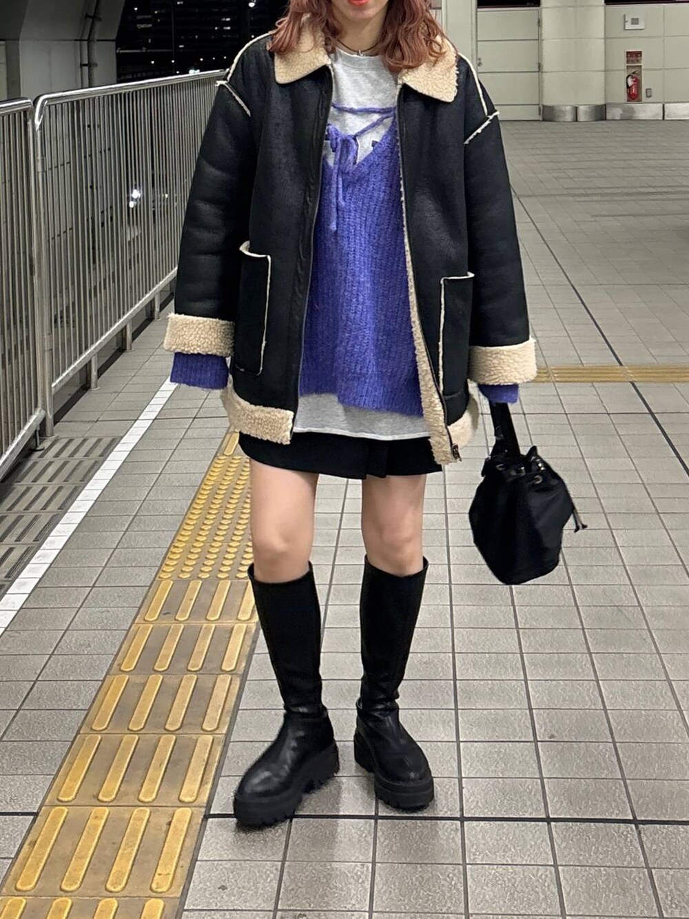 ブラック系のブルゾン、ブラック系のブーツ、ブラック系のショルダーバッグを着用したレディースの冬コーディネートの3枚目の写真