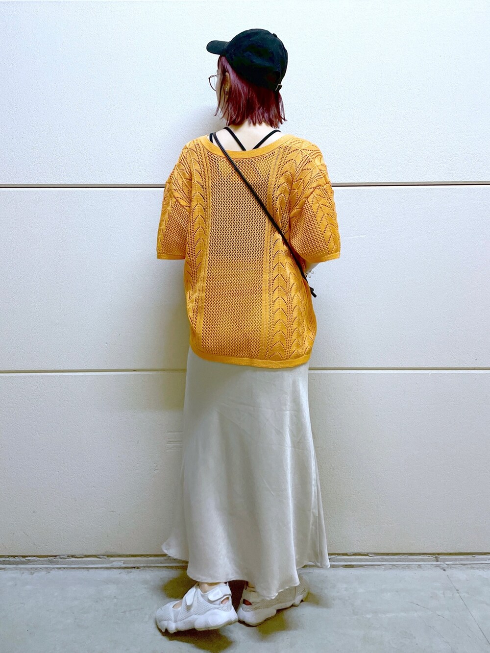 ブラック系のTシャツ/カットソー、オレンジ系のニット/セーター、ブラック系のスカートを着用したレディースの春コーディネートの4枚目の写真