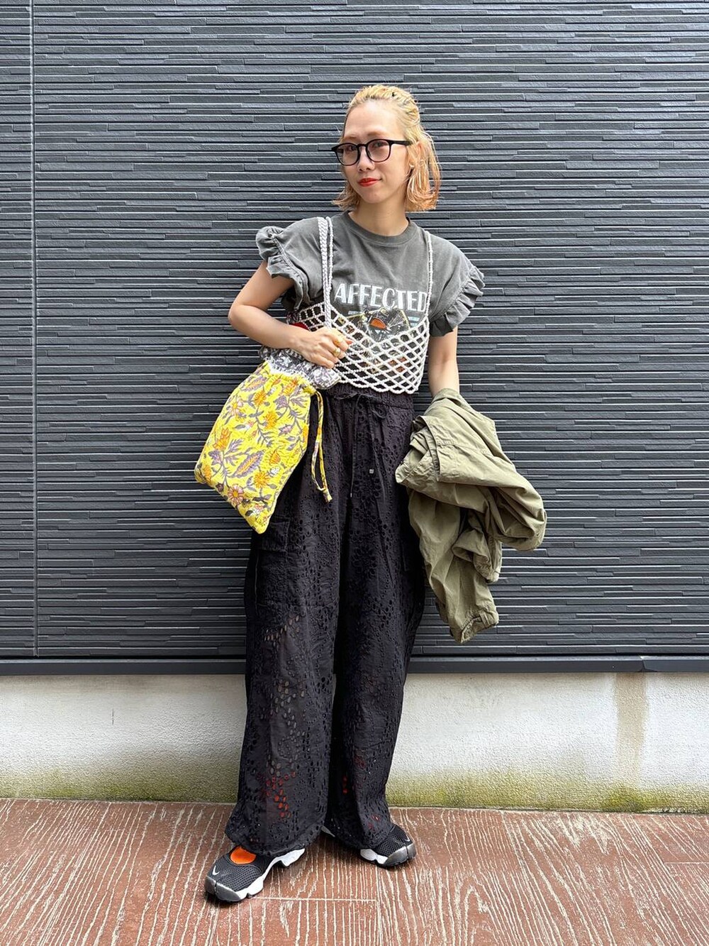 ブラック系のカーゴパンツ、イエロー系のトートバッグ、ホワイト系のベストを着用したレディースの春コーディネートの6枚目の写真