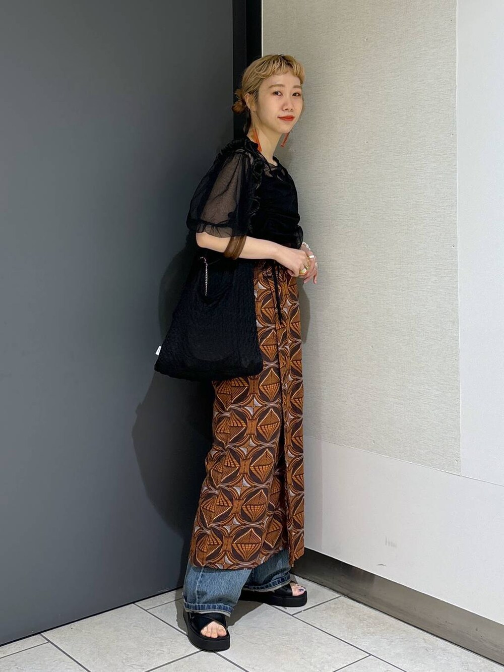 ブラック系のトートバッグ、ブラウン系のスカート、ブラック系のサンダルを着用したレディースの春コーディネートの2枚目の写真